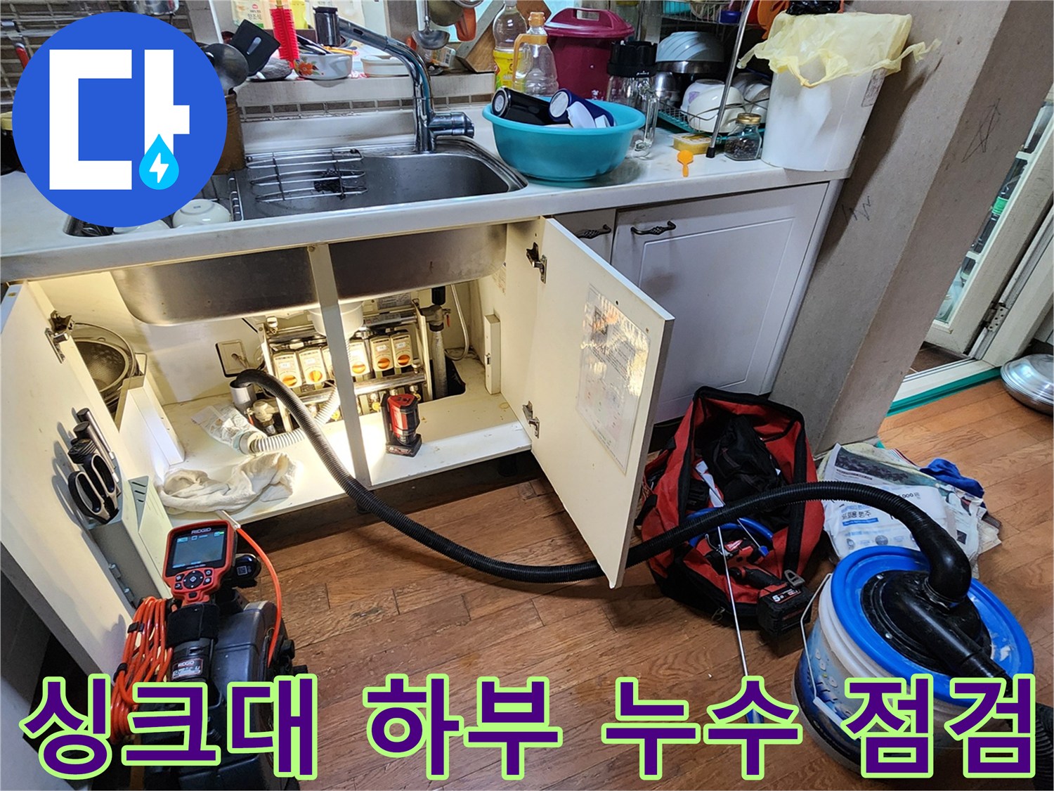 싱크대 아래 배관 연결 부위와 석션기 장비의 작업 모습