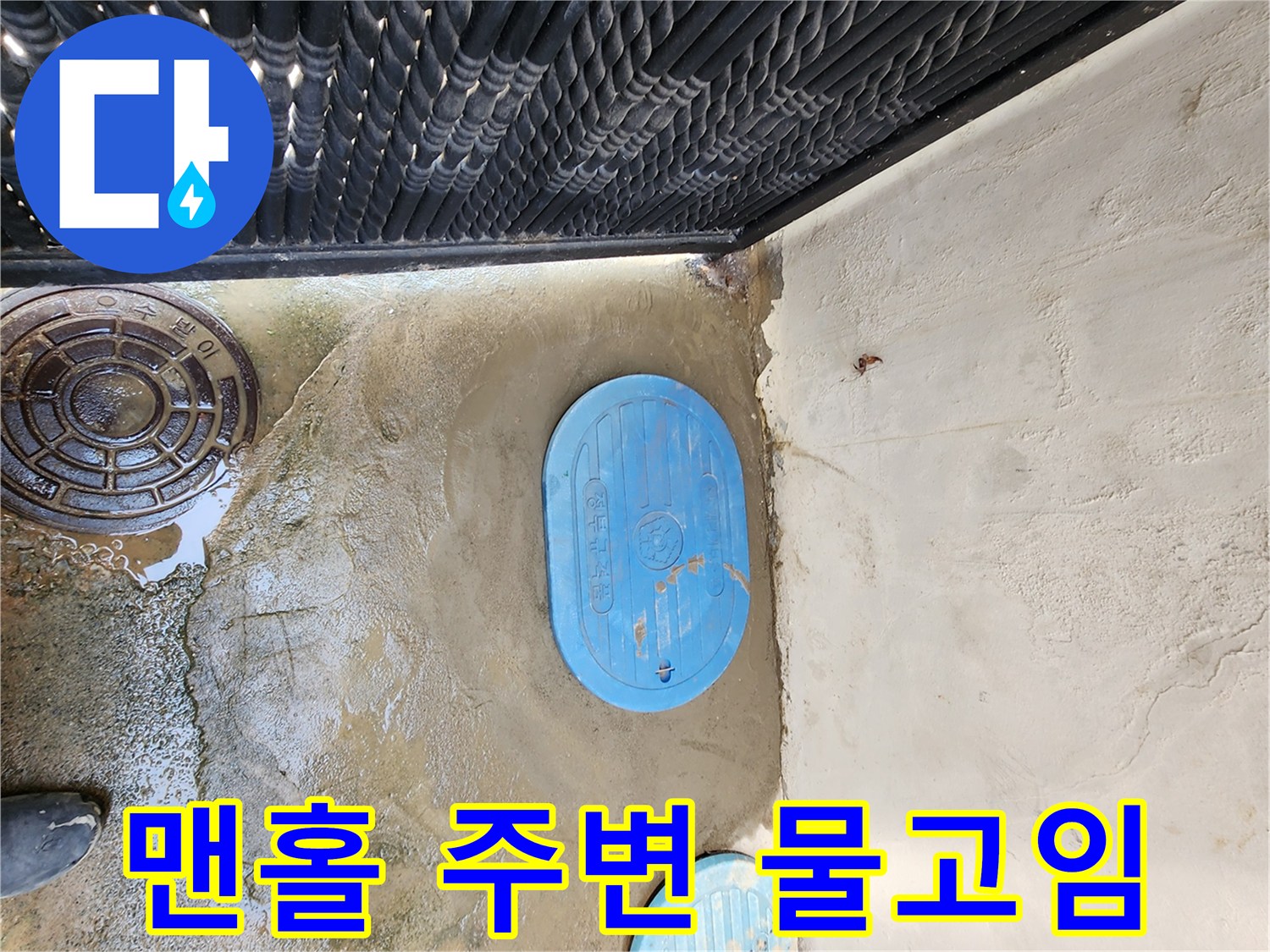 파란색 맨홀 뚜껑 주변에 물이 고여 있는 현장 모습
