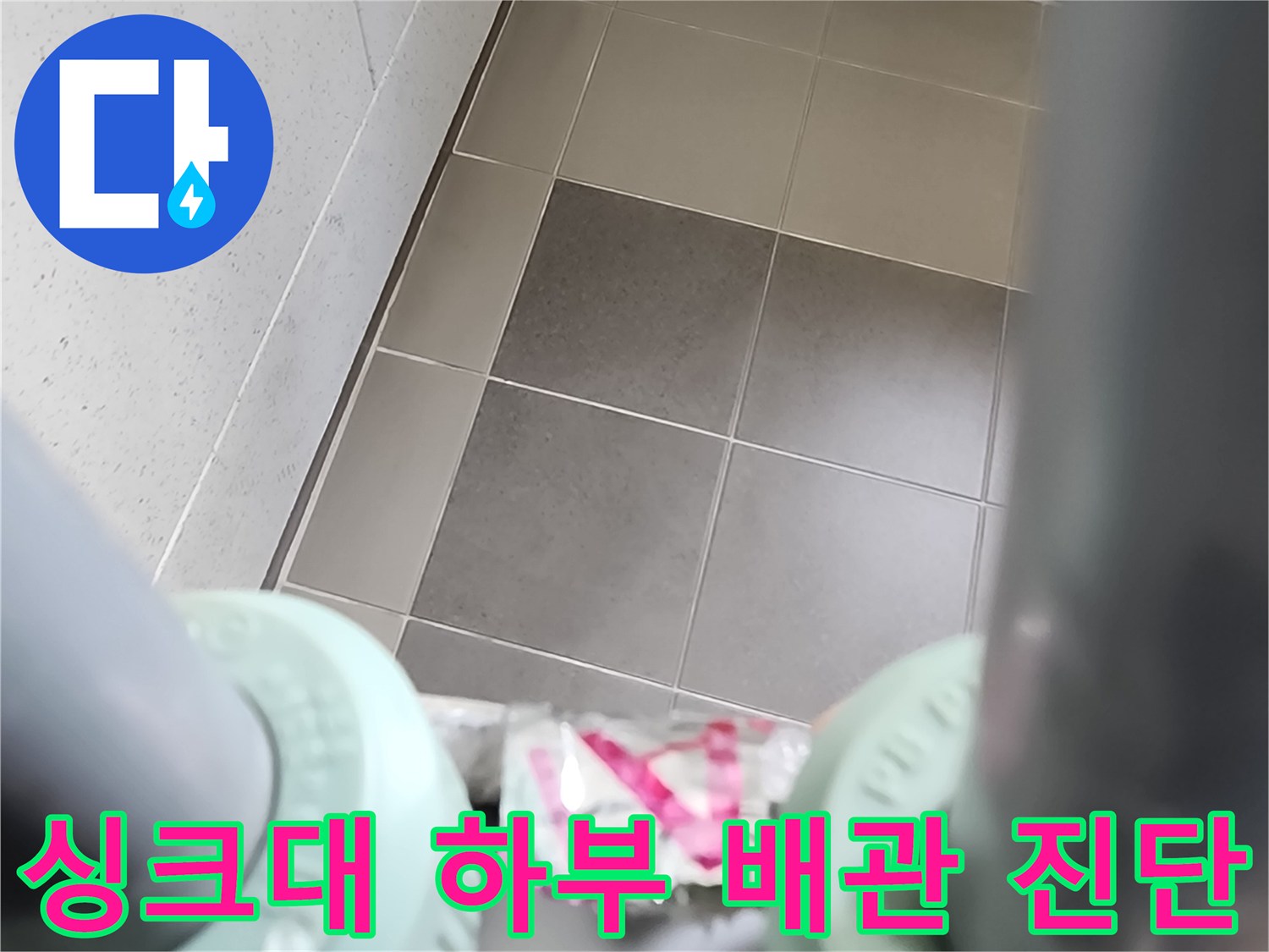 싱크대 아래쪽 타일 벽면과 배관 연결 부위의 근접 촬영