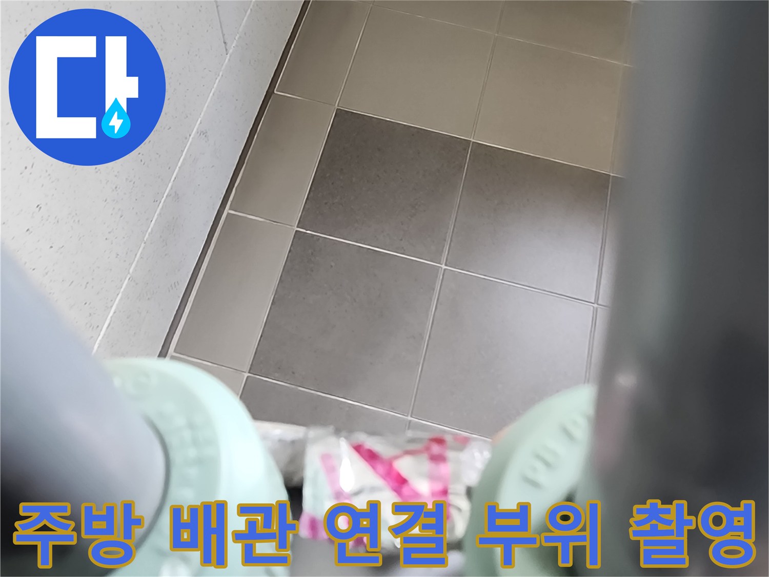 싱크대 하단 배관 부속과 바닥 타일의 근접 사진