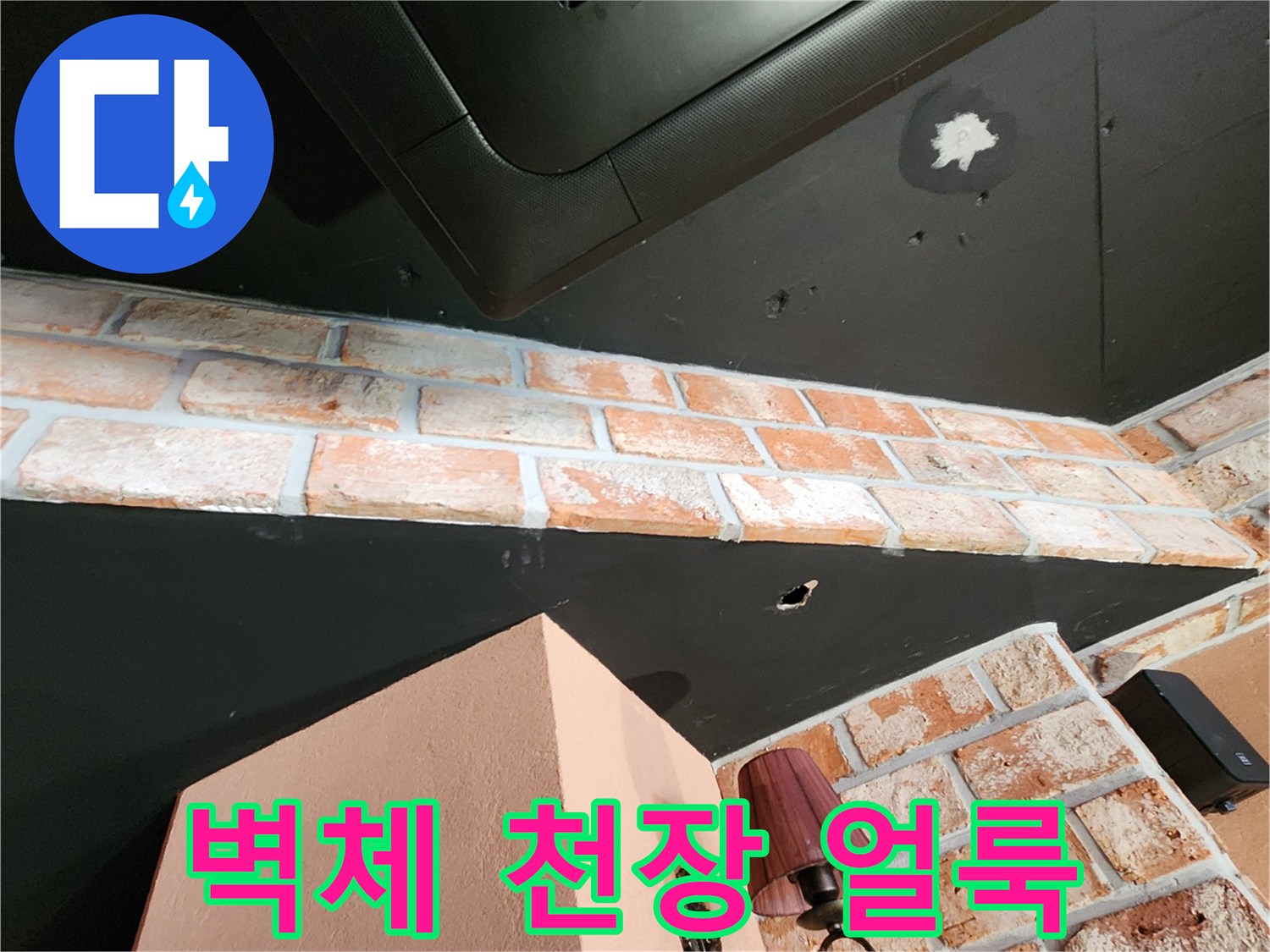 검은색 천장판과 벽돌 벽 사이의 하얀 누수 흔적