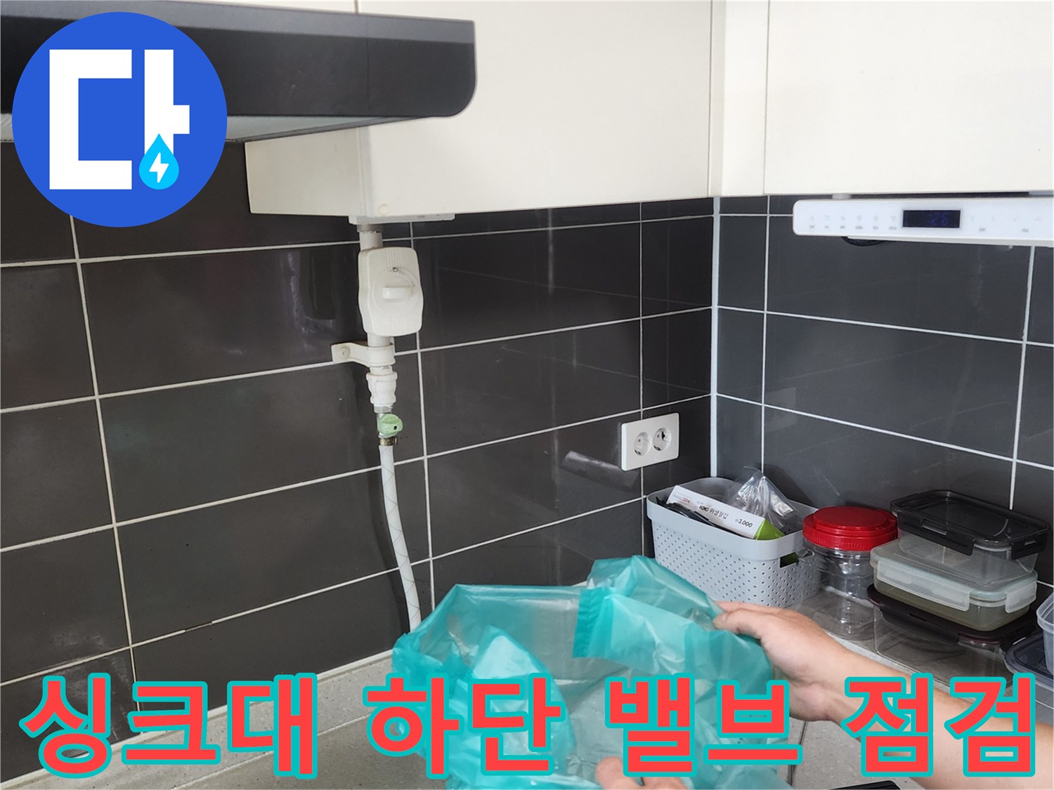 싱크대 아래쪽 배관 연결부와 급수 밸브를 살피는 장면