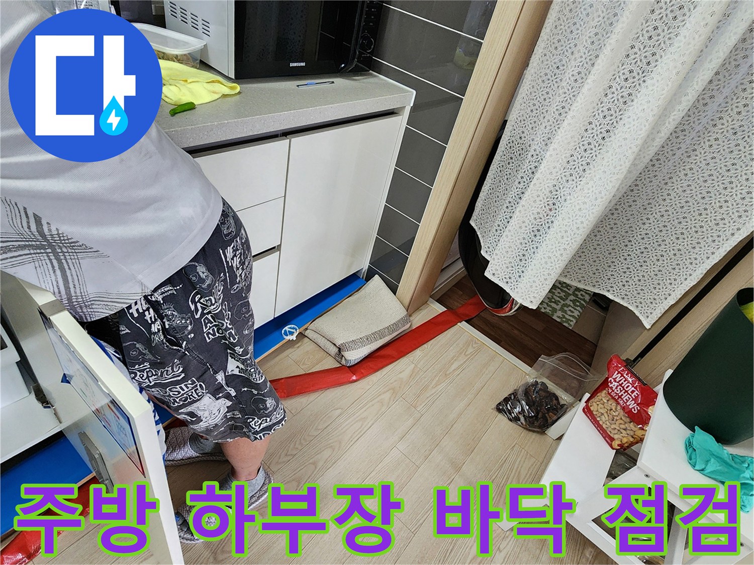 싱크대 아래쪽 배관 주변의 물샘 흔적과 임시 차단막