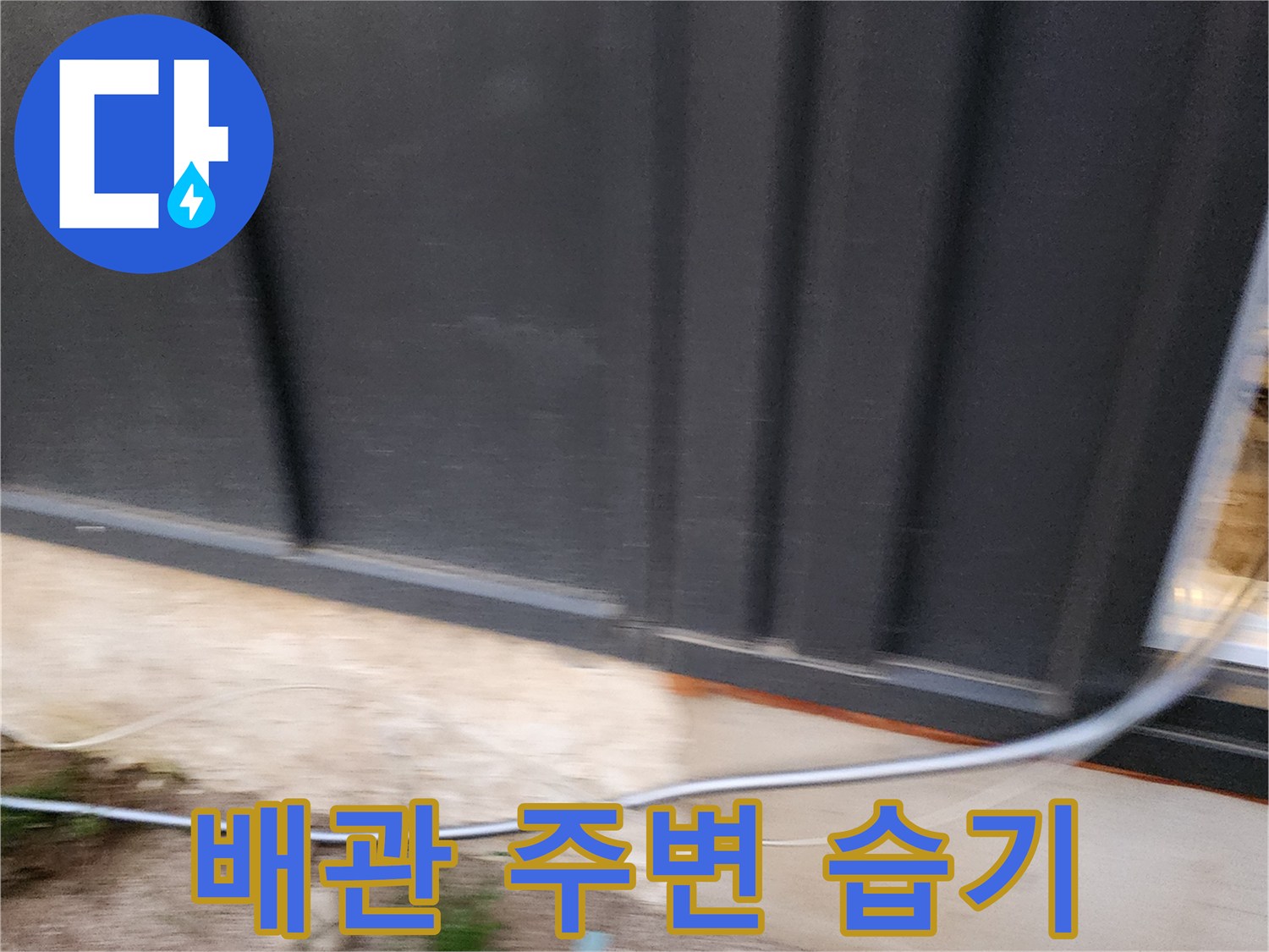 건물 외벽 하단 배관 근처의 젖은 마감재 상태