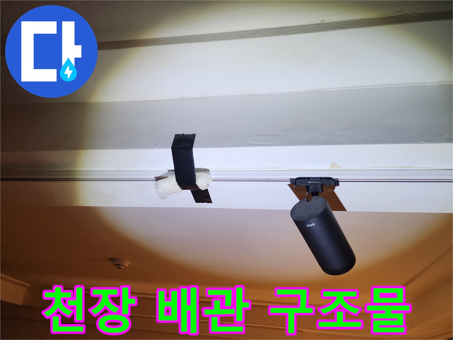 천장 프레임에 설치된 검은색 배관 장치 사진입니다
