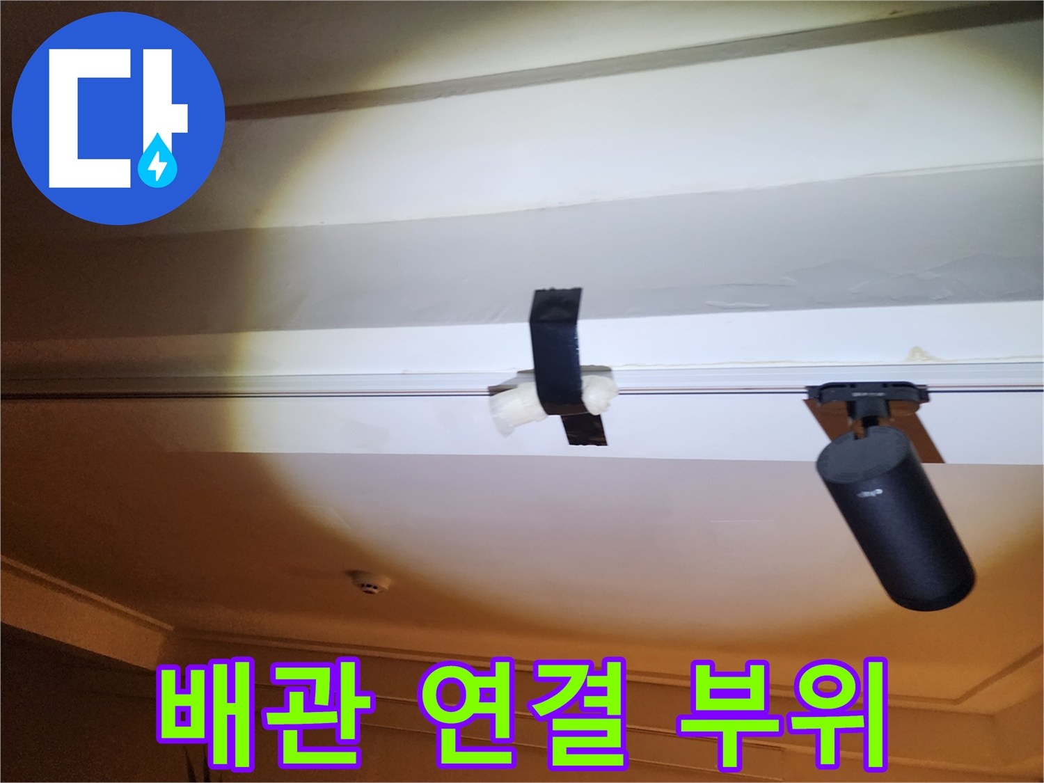 천장에 노출된 배관과 검은색 고정 장치입니다.