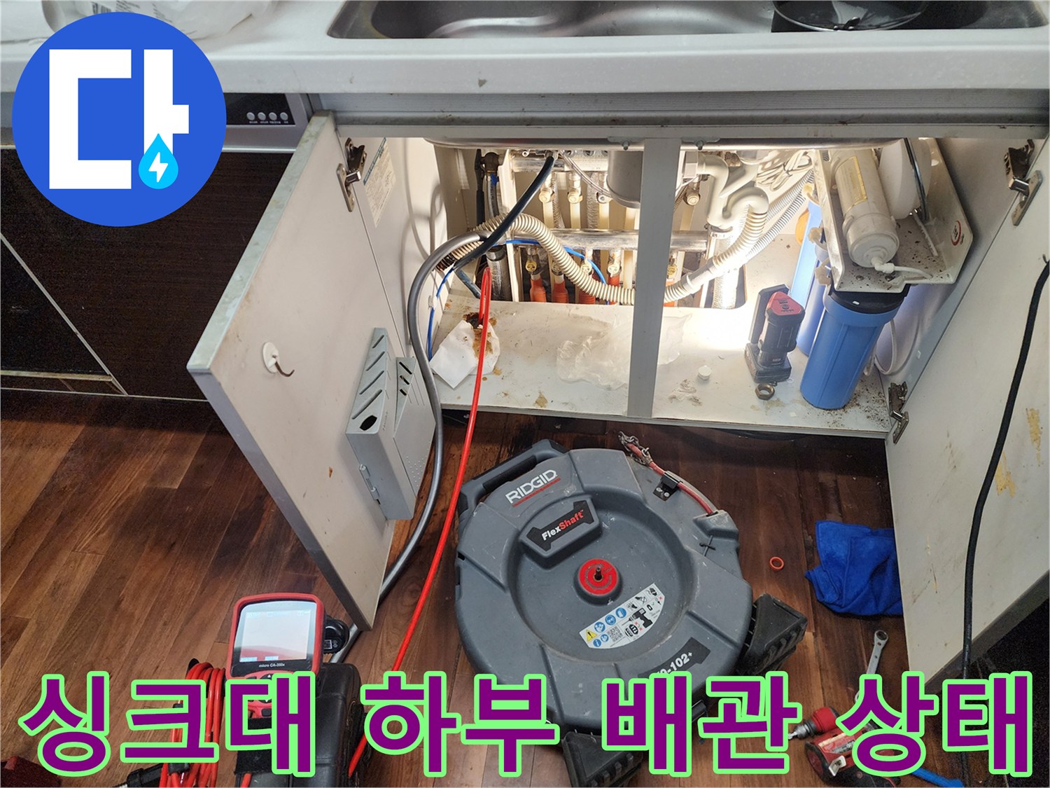 주방 싱크대 하단-복잡한 배관과 점검 장비 모습