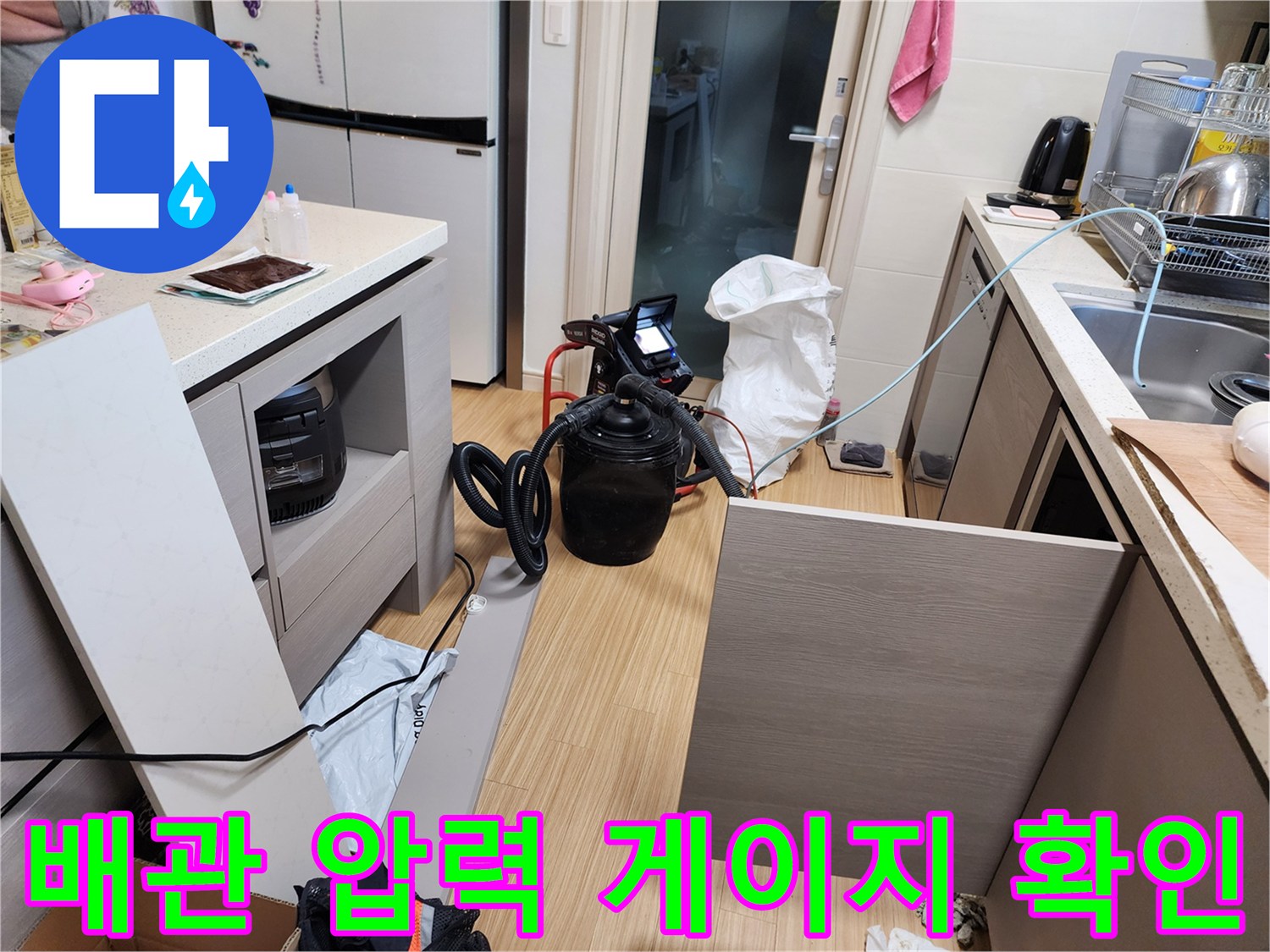 싱크대 하부 배관에 연결된 공압 테스트 장비와 호스 뭉치