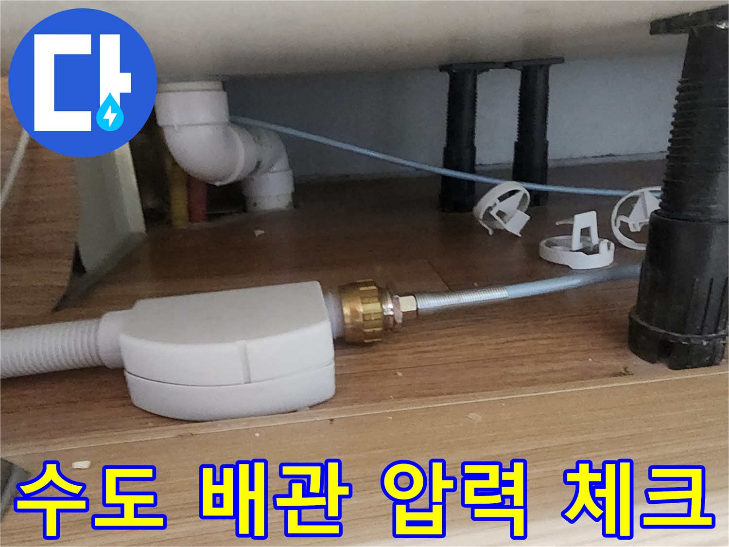 싱크대 하부장 바닥에 설치된 배관 연결 부위와 테스트 호스