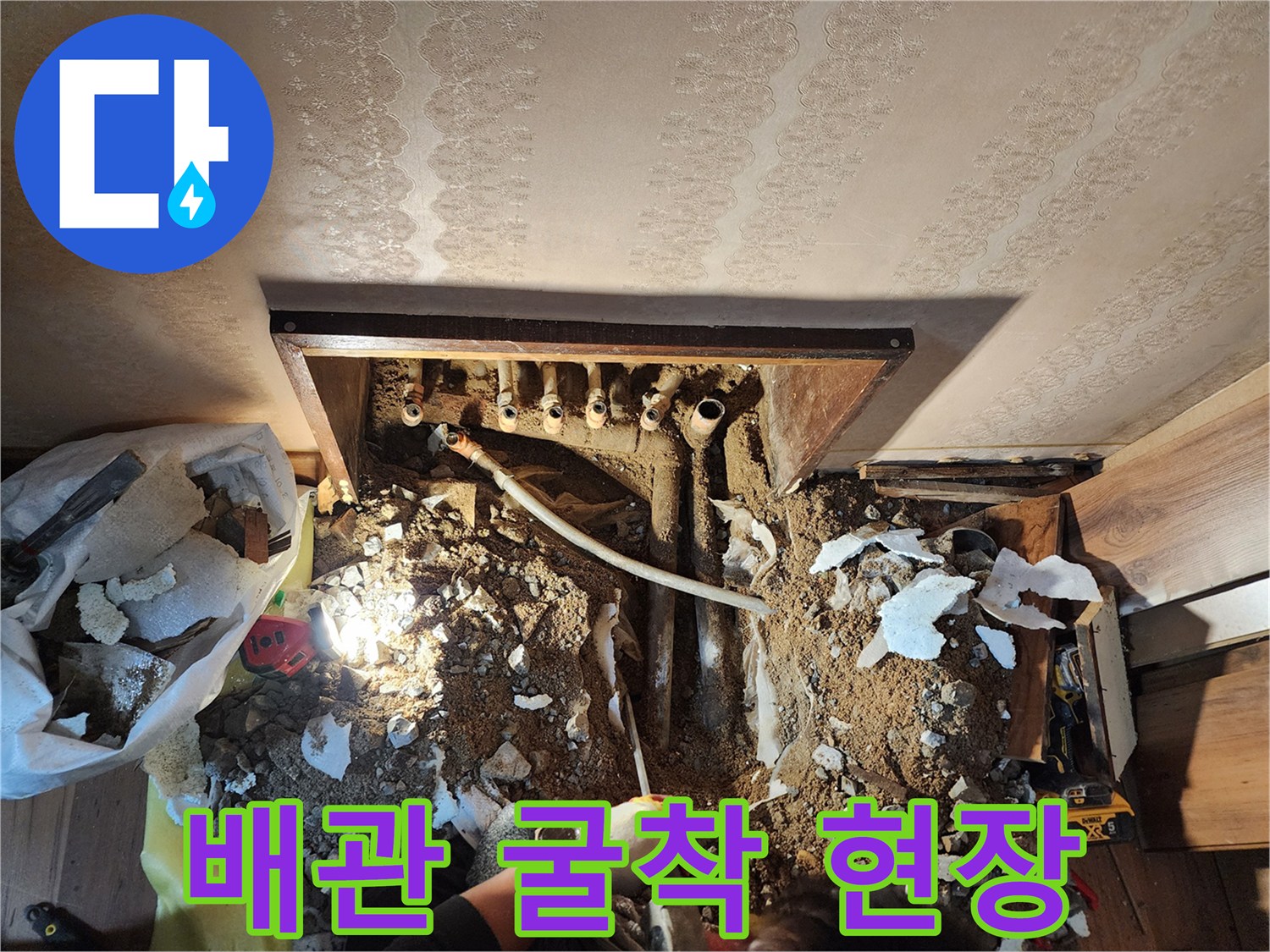 콘크리트 층을 제거하여 노출된 배관과 젖은 흙의 모습