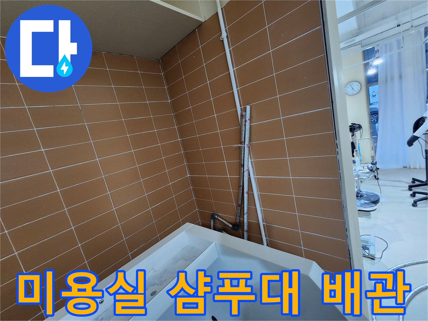 미용실 샴푸대 주변의 타일 벽면과 노출된 배관 상태