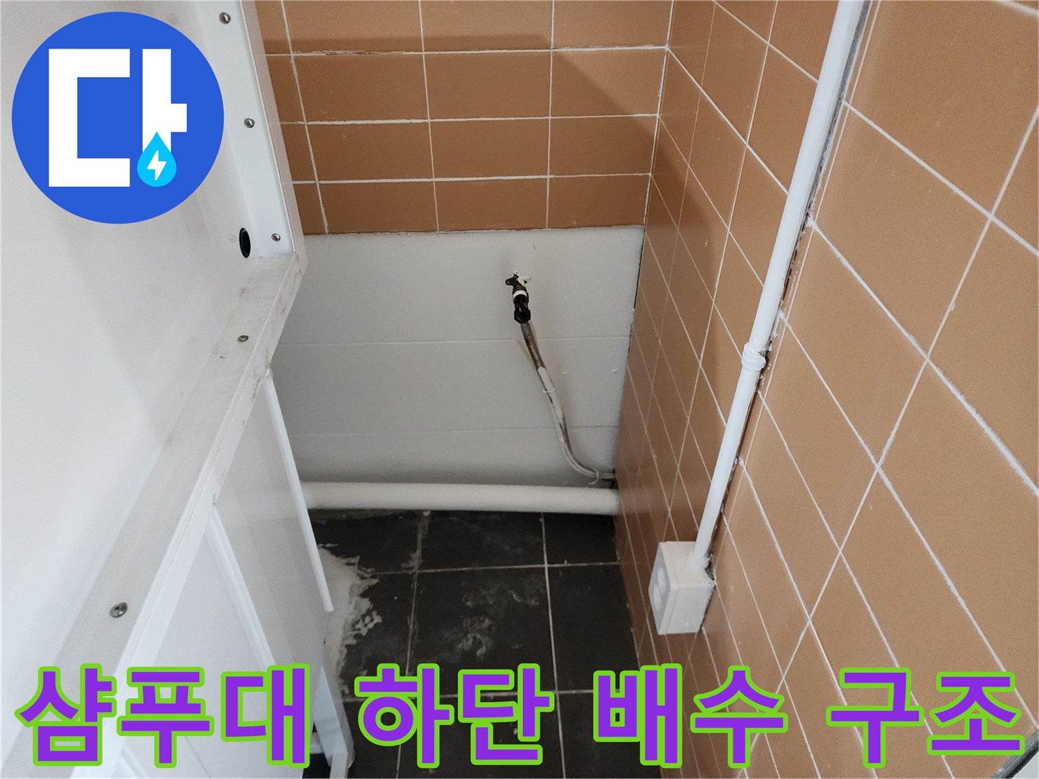 타일 벽면과 연결된 샴푸대용 배수 배관의 현장 사진입니다.