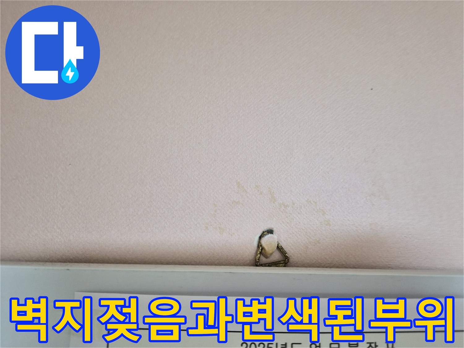 누수로 인해 젖고 변색된 천장 도배지 부근