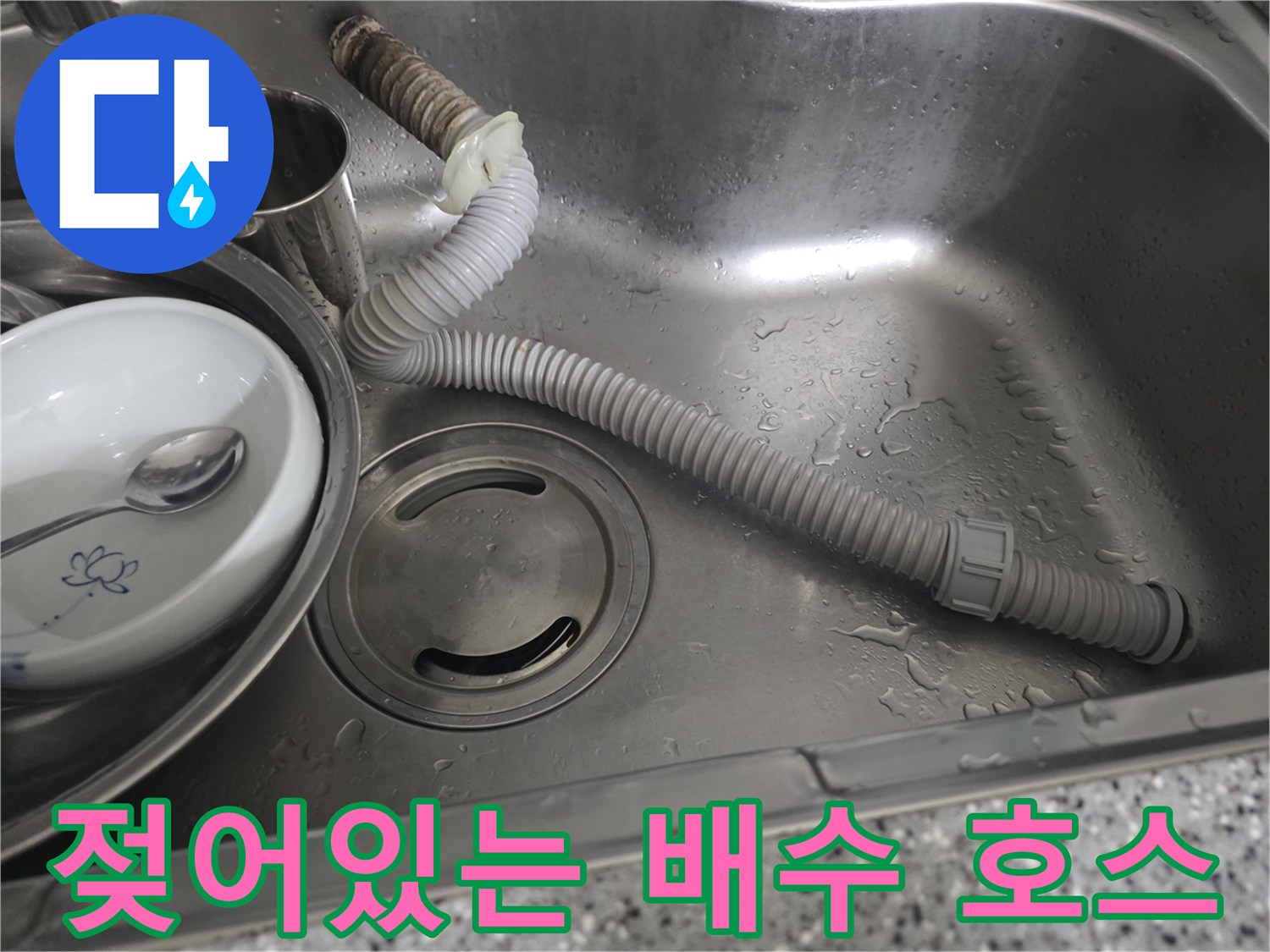 물이 맺힌 회색 주름관과 싱크대 배수구의 모습