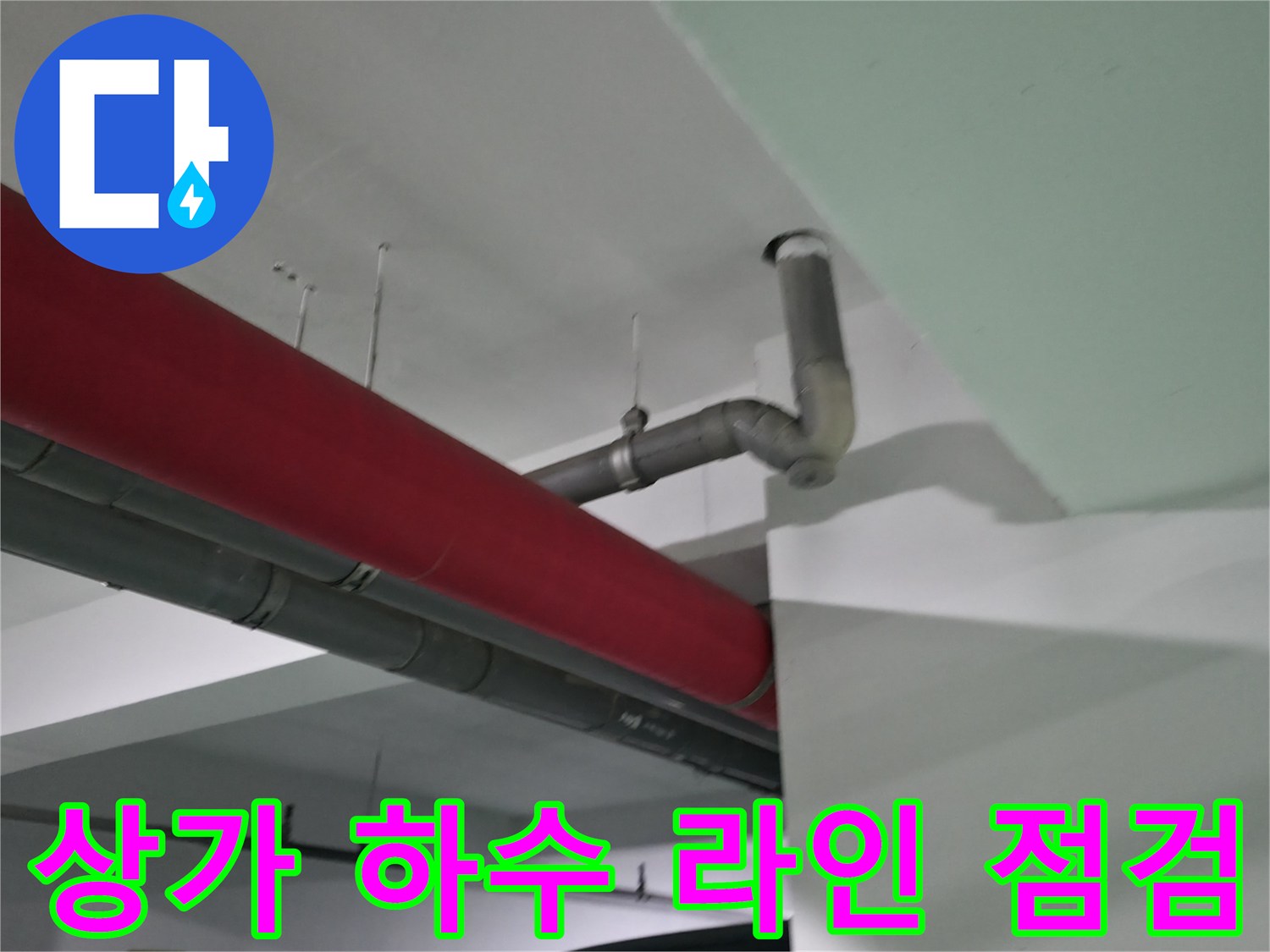 회색 배관과 빨간 마감재가 겹쳐진 천장 내부의 배수 구조