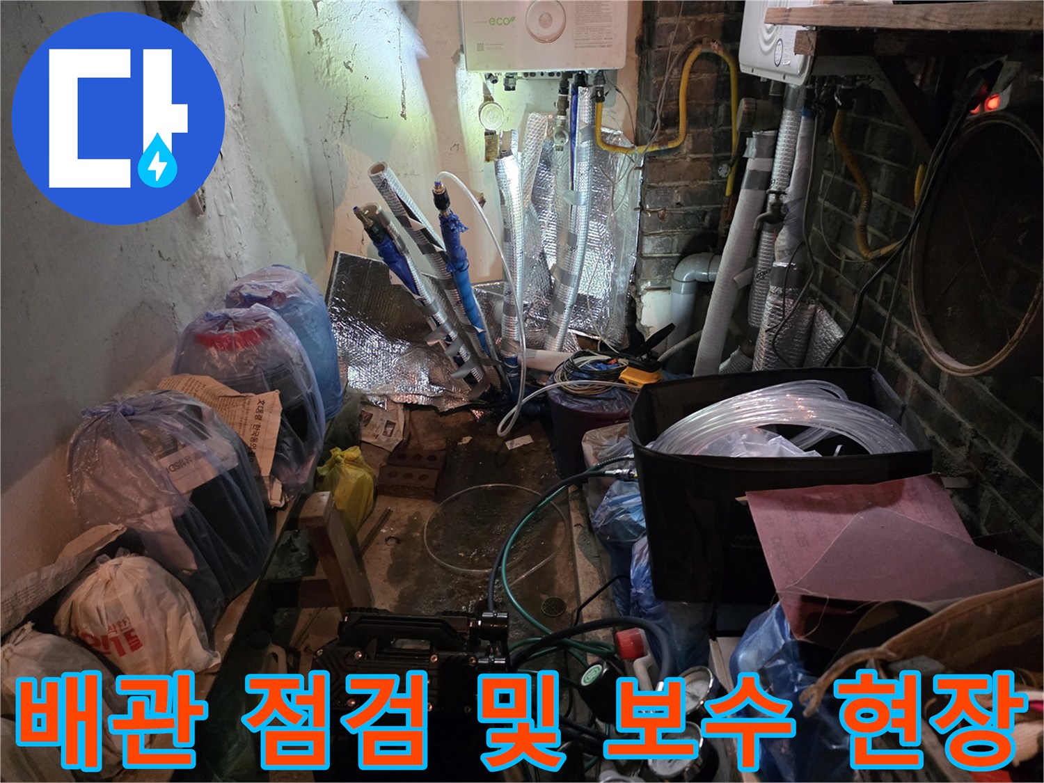 주방 하부의 복잡한 배관 상태와 작업용 장비