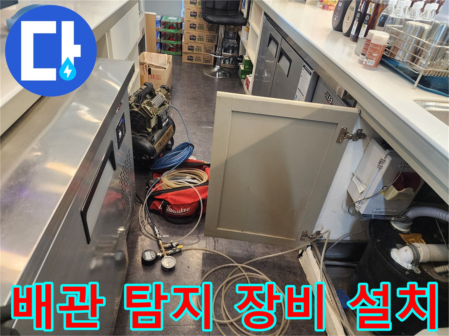 싱크대 밑 바닥의 젖은 부위와 배관 점검용 압력계 모습