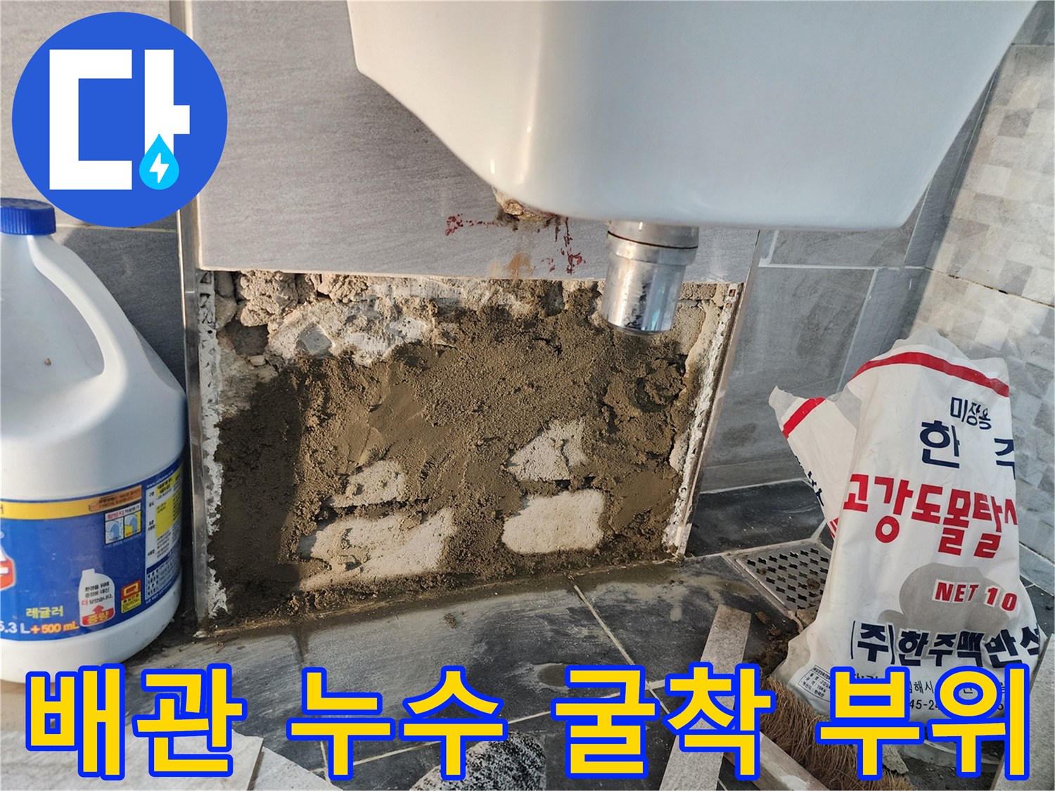 누수가 발생한 변기 뒷면 배관을 확인하기 위해 타일을 파낸 현장 사진입니다.