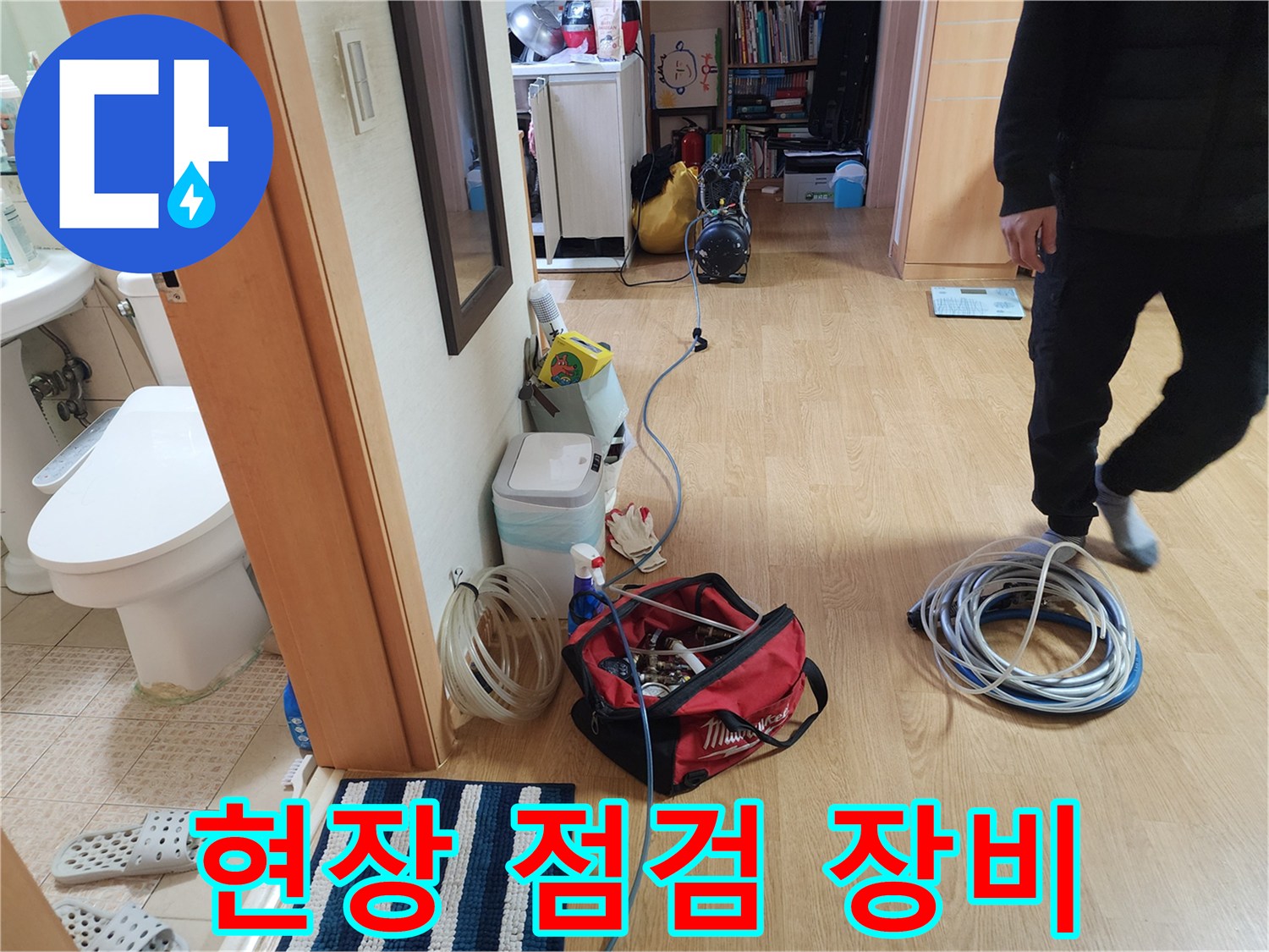 거실 바닥에 준비된 빨간 공구함과 파란색 압력 체크 호스