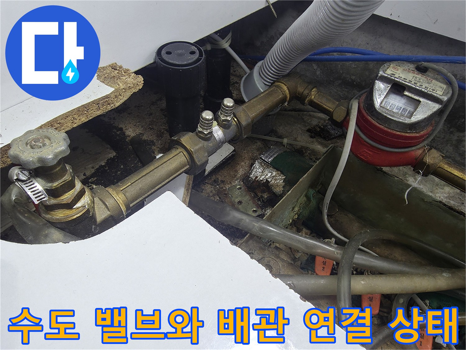 싱크대 아래 설치된 수도 계량기와 금속 재질의 급수 배관 상세 사진