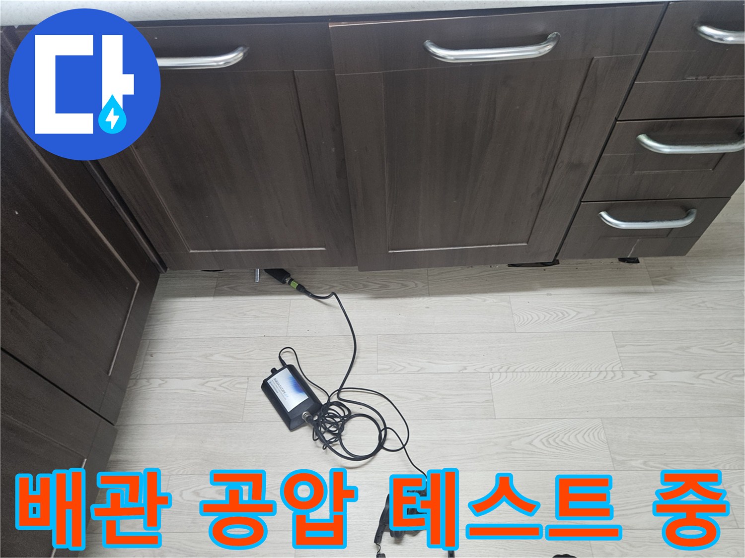 싱크대 하부 배관에 연결된 압력 측정 장비와 검사 호스
