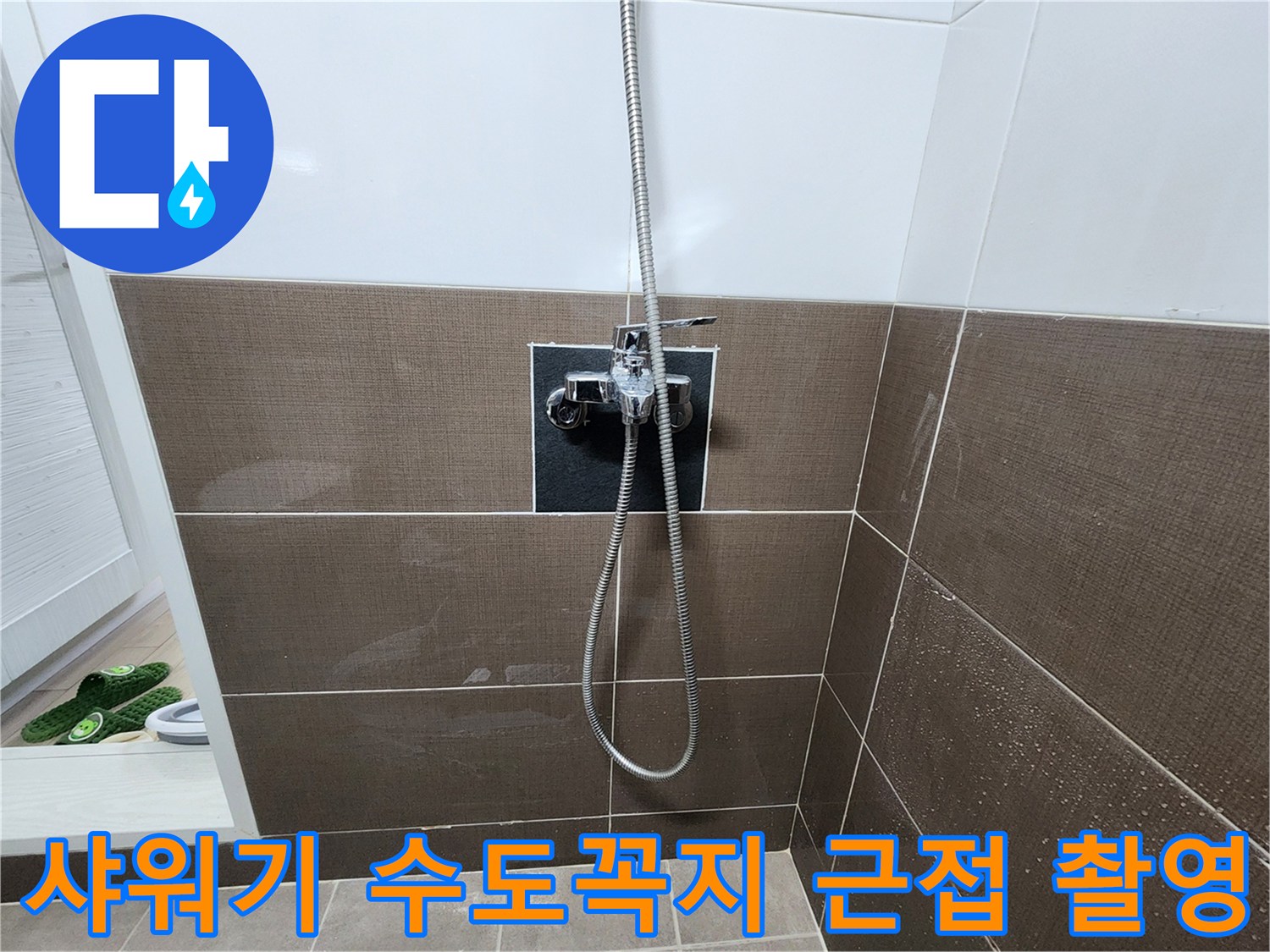 금속 재질의 샤워 수전과 벽면 타일 부위