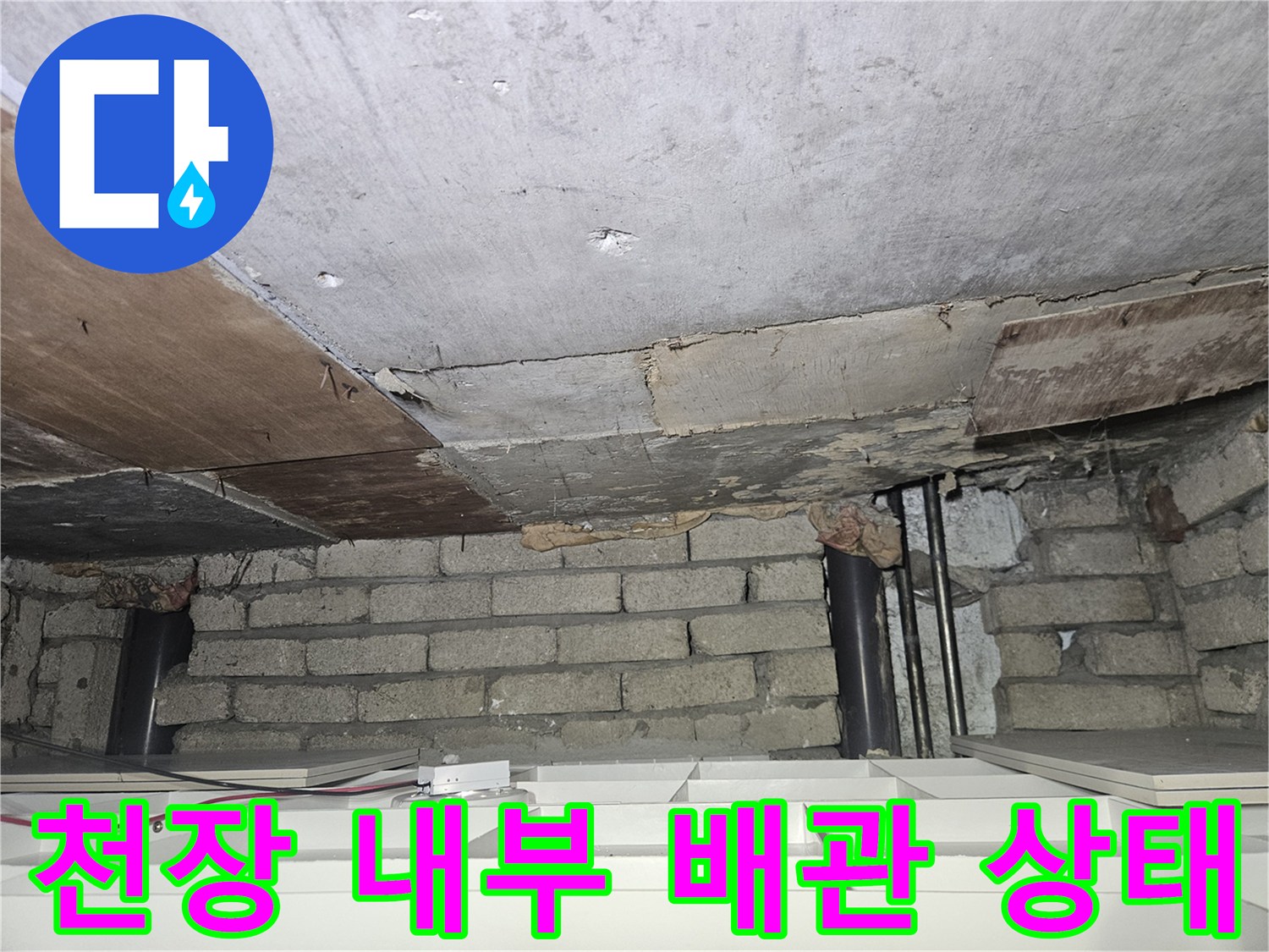 건물 천장 하부-노출된 검은색 배관과 콘크리트 마감 부위