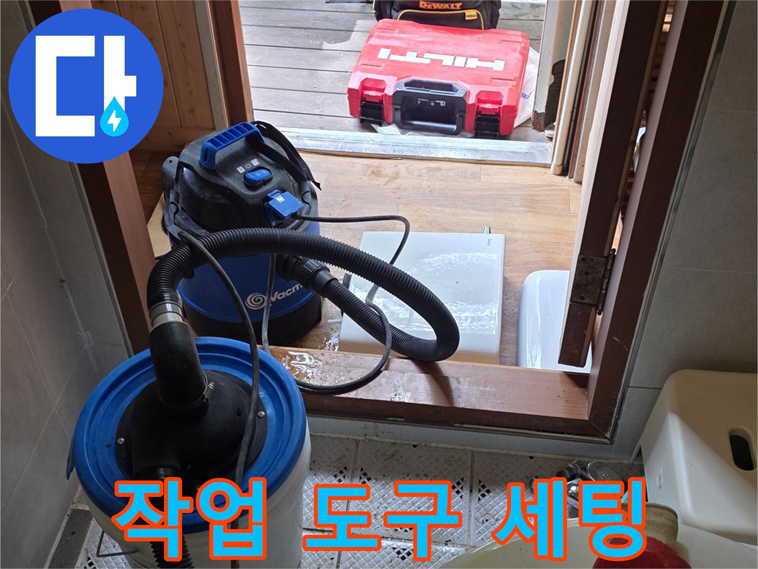 변기 옆에 놓여 있는-청소용 진공기와 작업 장갑