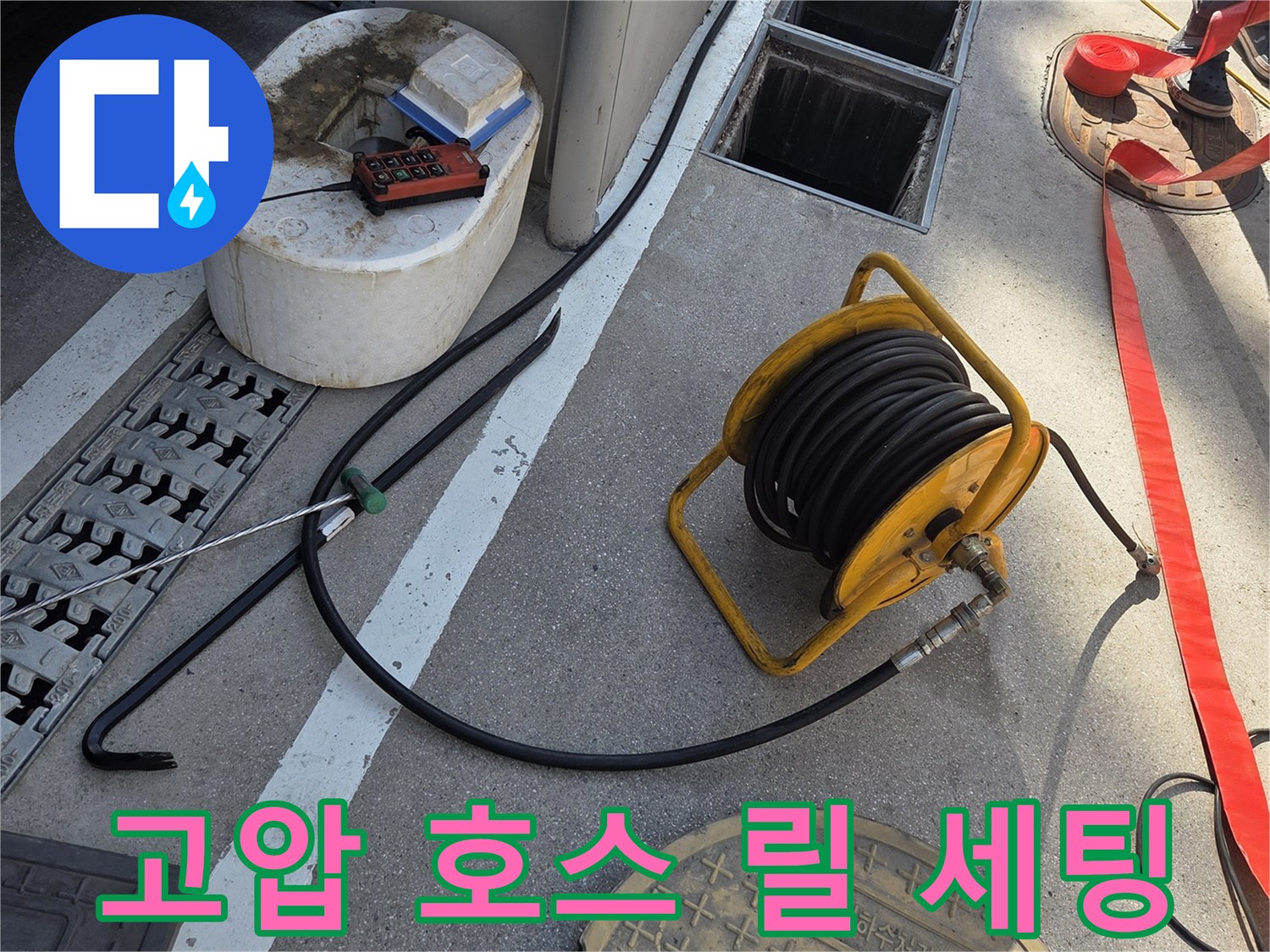 맨홀 옆에 준비된 노란색 고압 호스 릴과 작업 도구