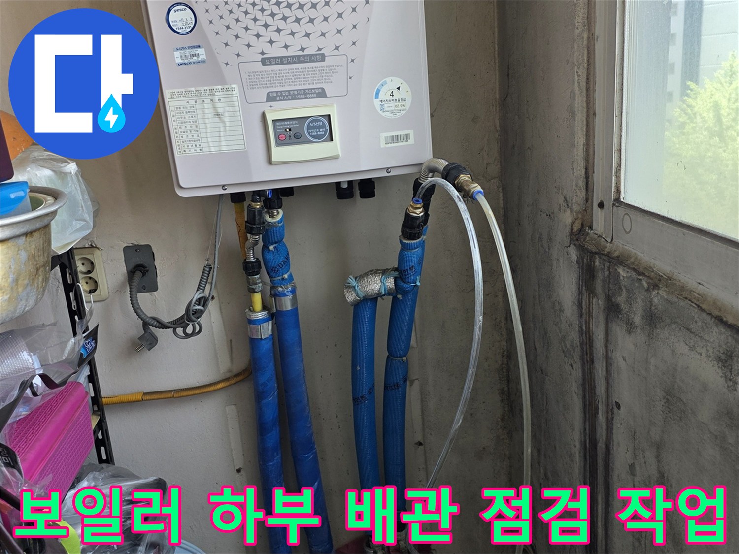 보일러 아래 파란색 배관과 흰색 호스가 연결된 부위를 촬영한 사진