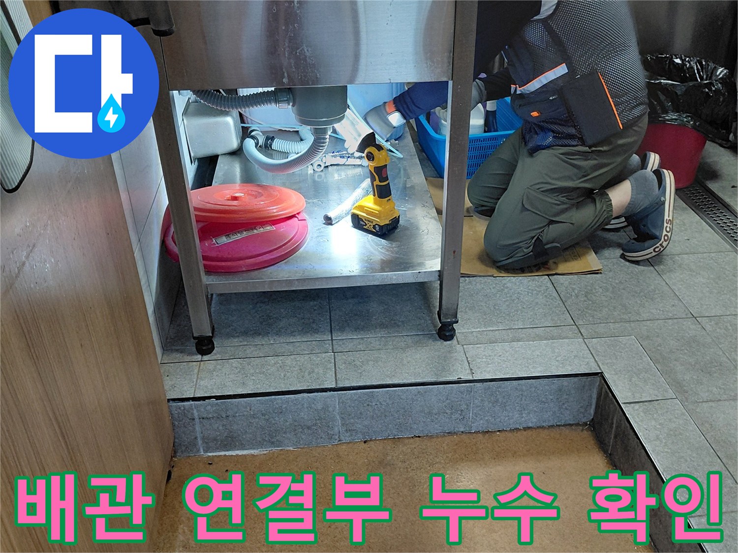싱크대 하부 배관의 연결 부위와 전동 공구 작업 모습