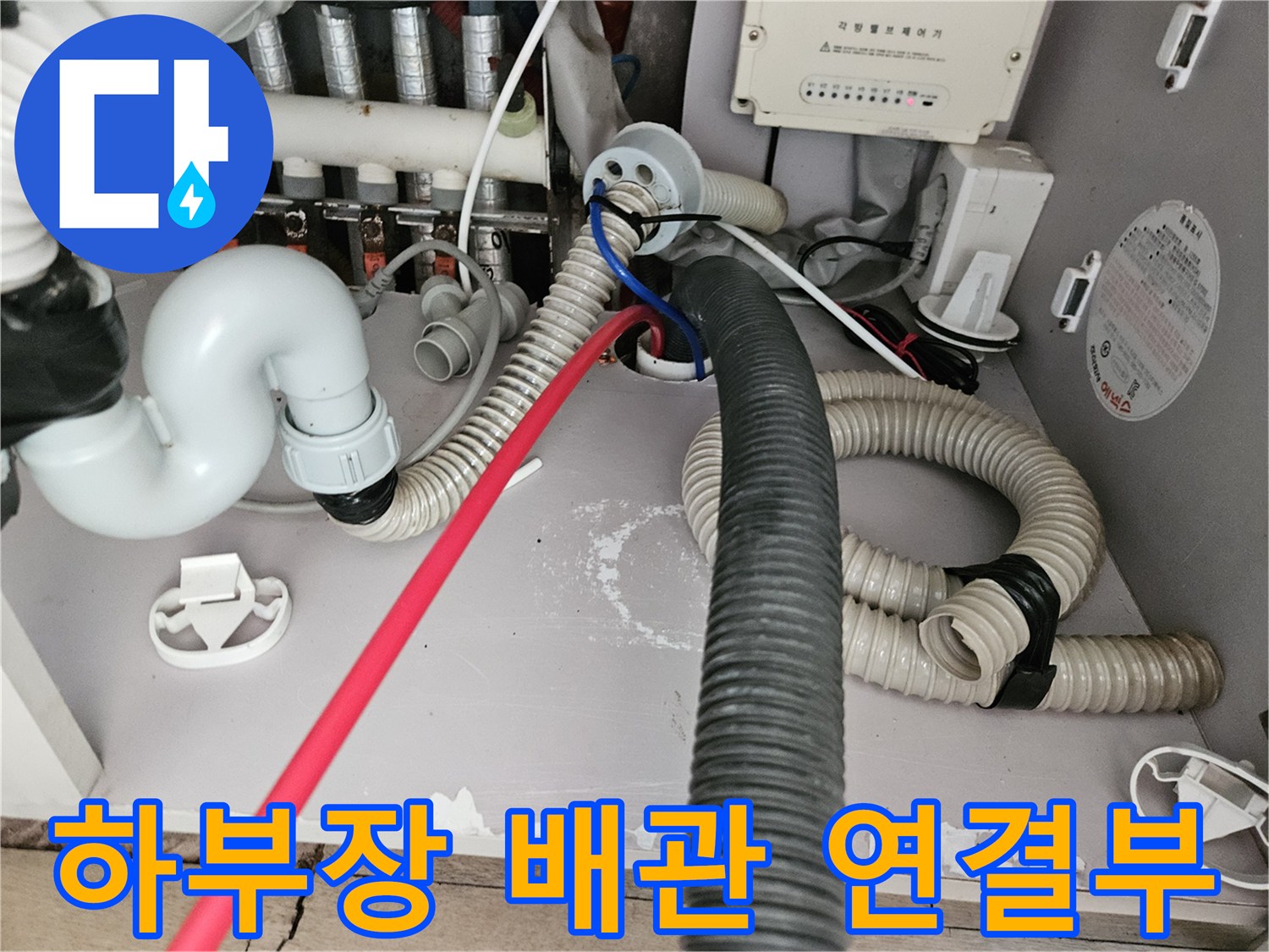 싱크대 하단-배수 호스와 분배기가 위치한 복잡한 배관 구조 사진