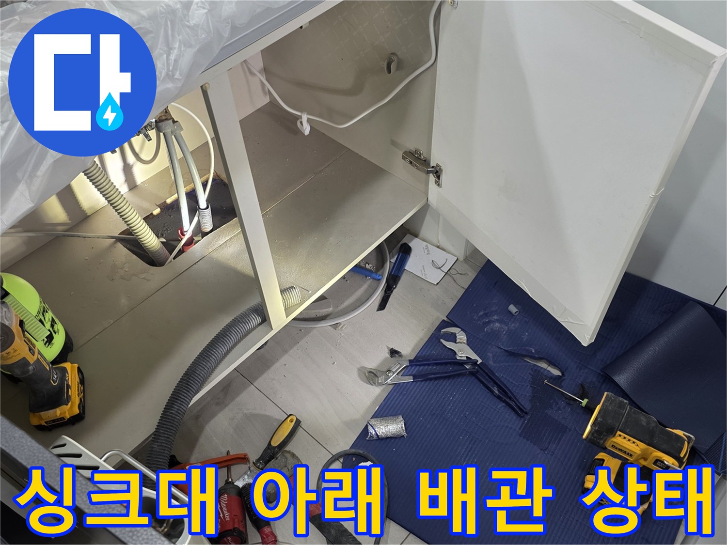 싱크대 하부 배관과 작업용 전동 드릴 및 공구들
