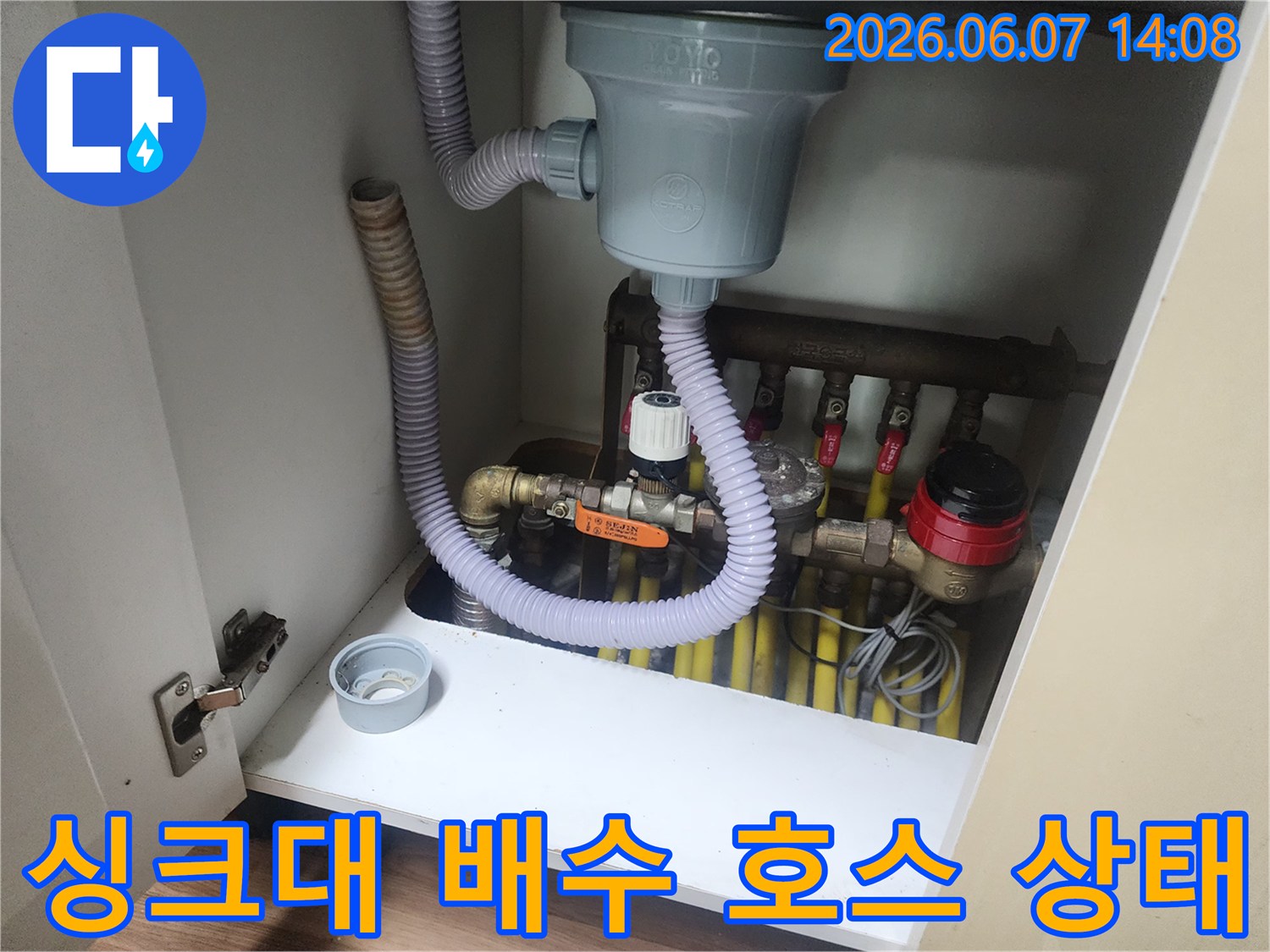 싱크대 하단부의 회색 주름관과 노란색 급수 배관들의 연결 모습입니다.