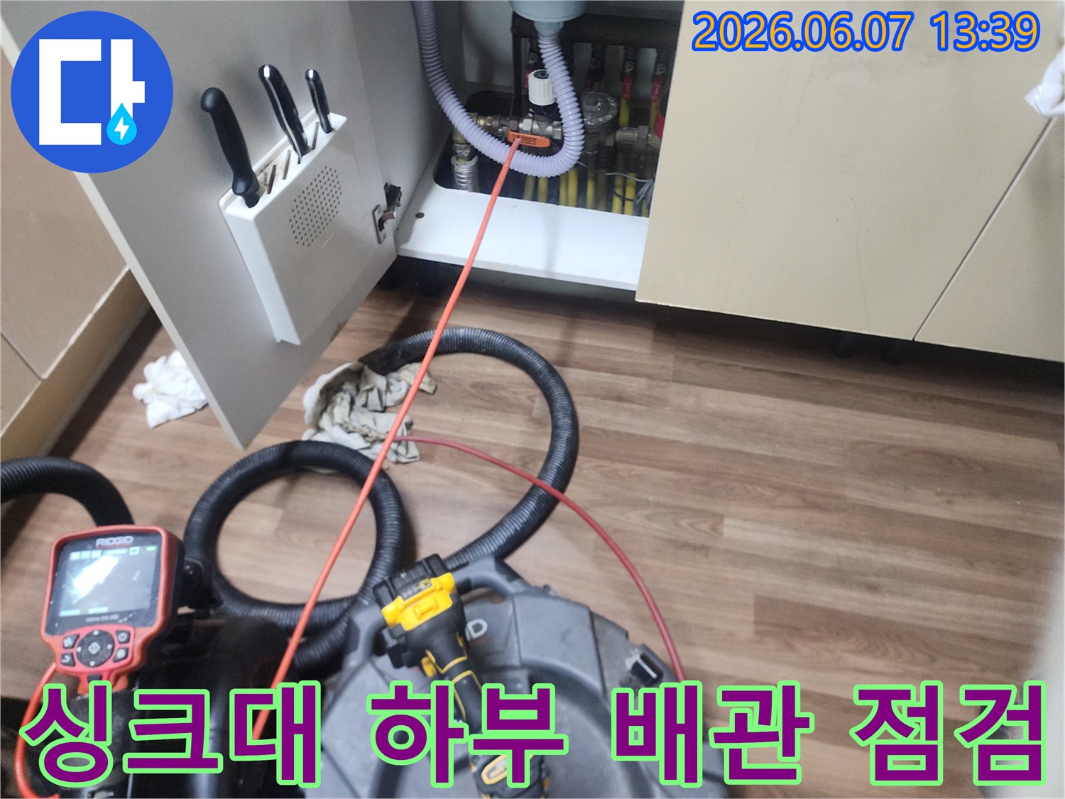 싱크대 하부장 내부의 배관과 작업 장비 모습입니다.