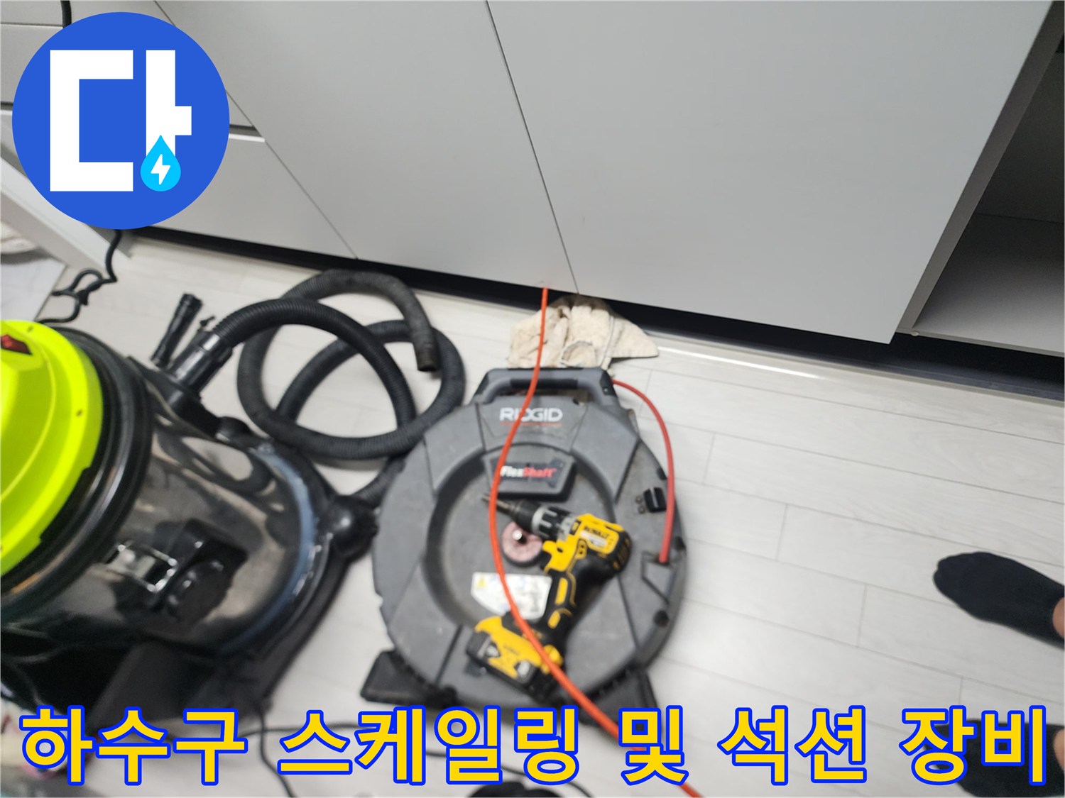 싱크대 하부 배관 세척을 위해 준비된 전문 장비와 전선 릴