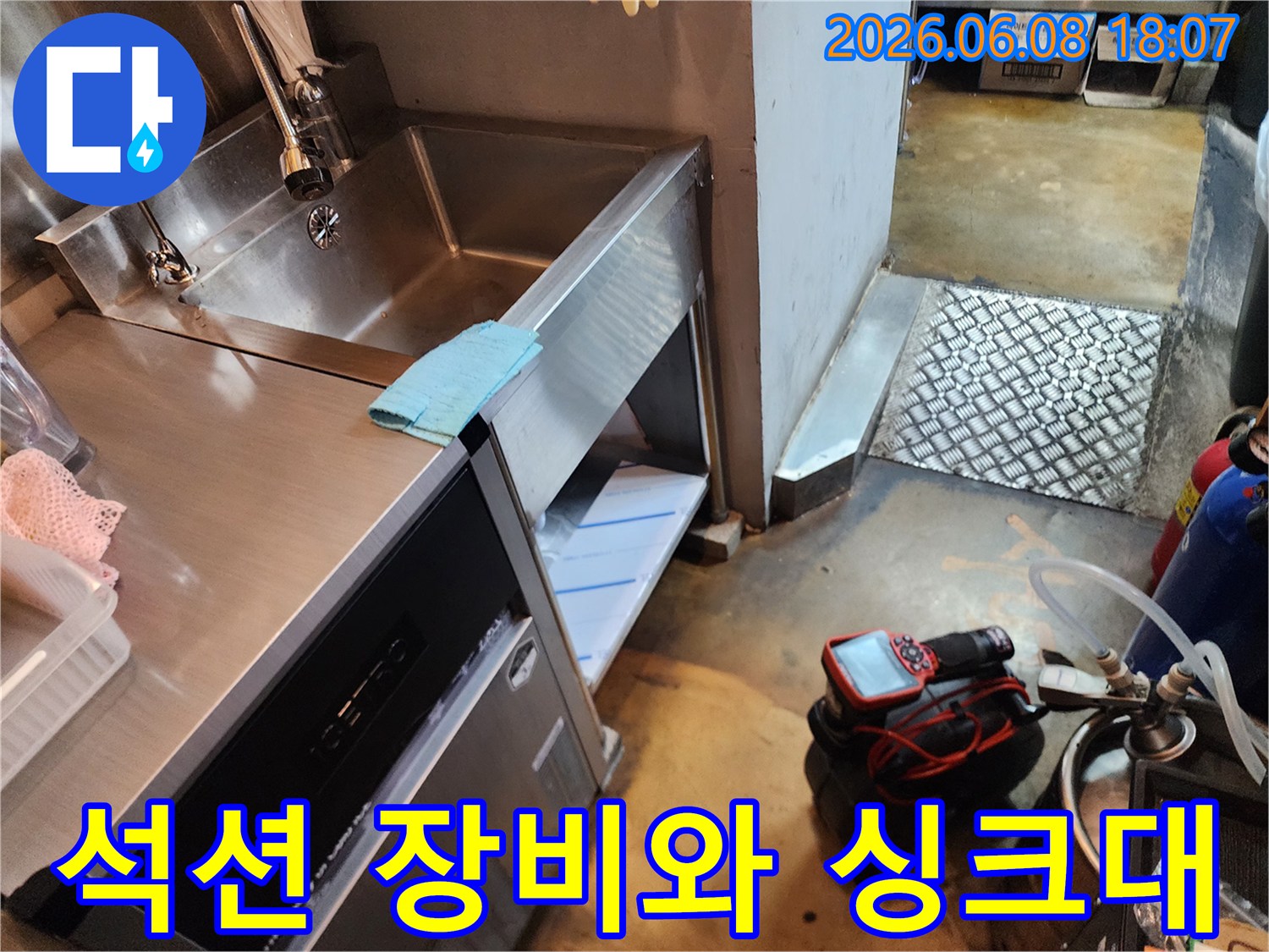 스테인리스 싱크대 아래 배치된 빨간색 배관 석션 장비 세트