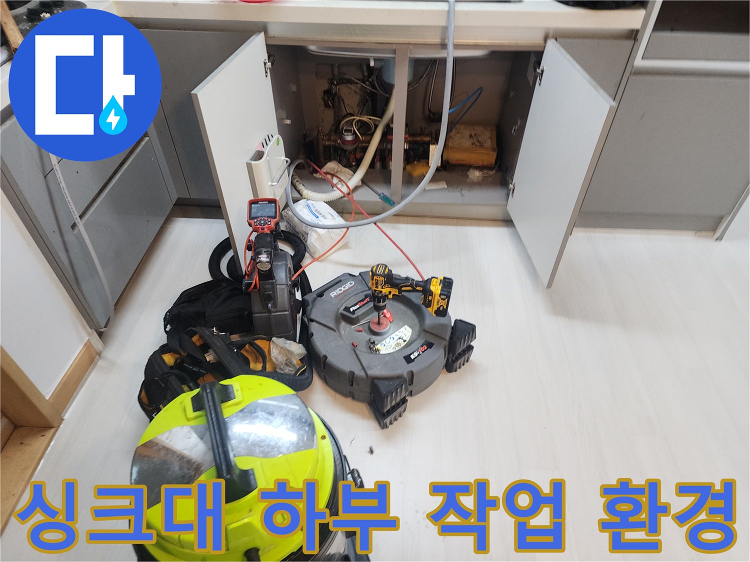 싱크대 아래 배관 청소 작업을 위해 정돈된 전문 장비와 도구들