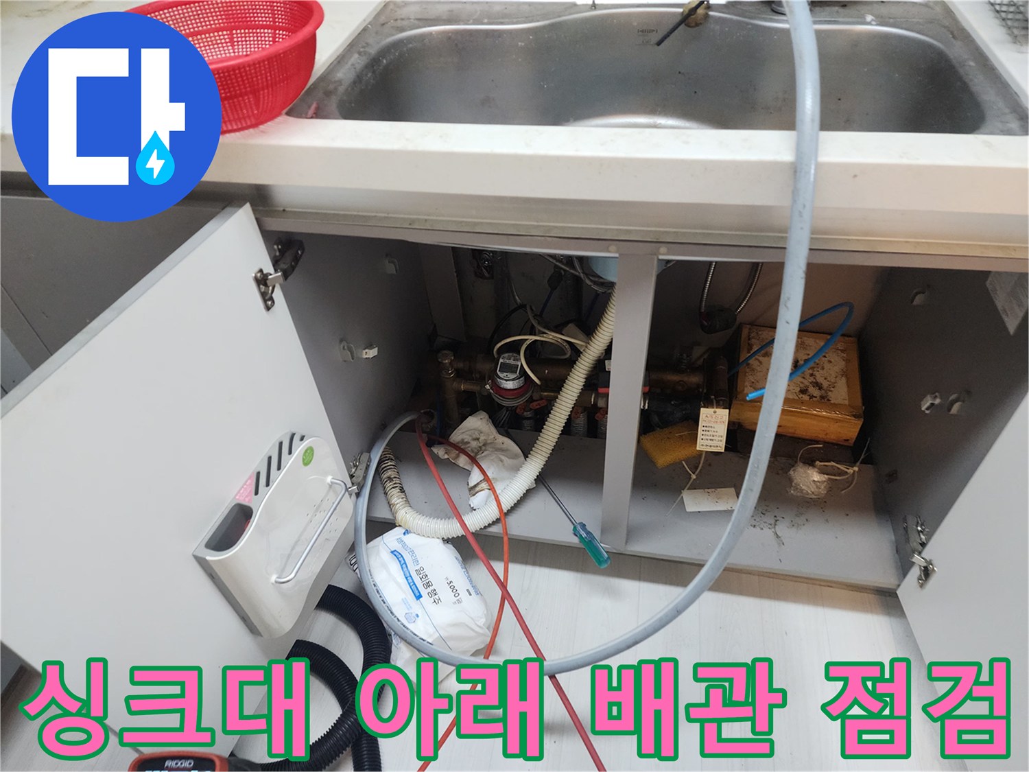 싱크대 하부장 내부의 급수 밸브와 배수 호스 모습