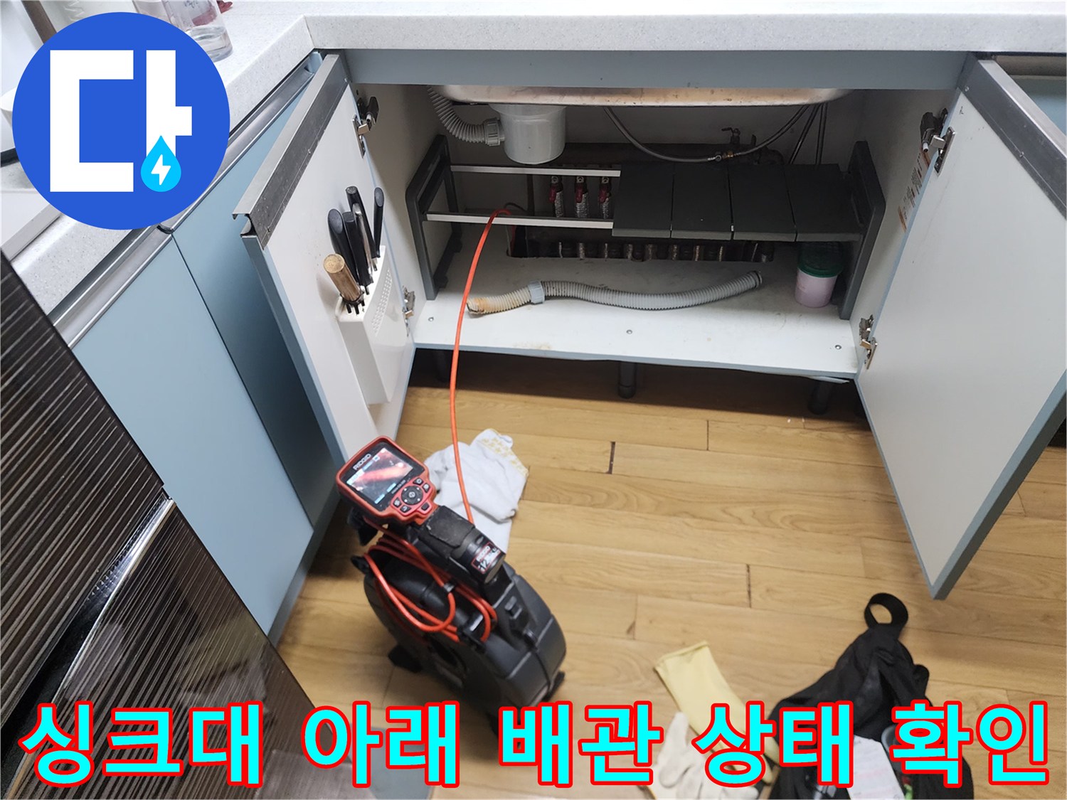 싱크대 하부장 내부의 배수 호스와 작업용 장비들