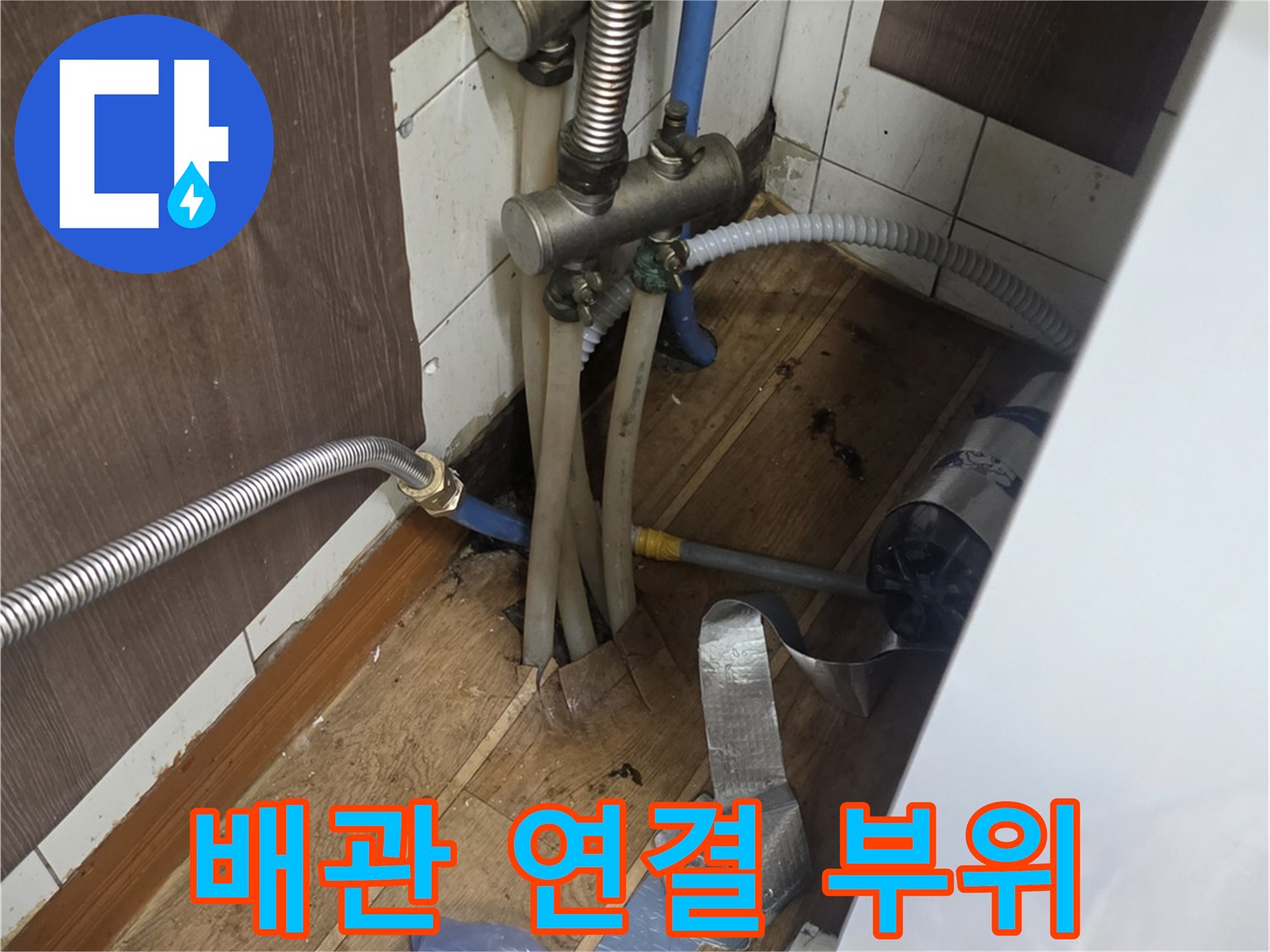 싱크대 하단 배관 뭉치와 은색 금속 부품의 모습