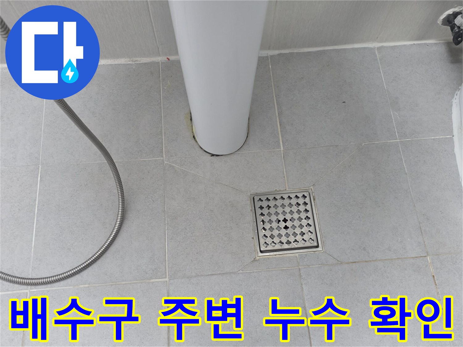 하얀색 타일 바닥에 위치한 배수구의 상태를 촬영함
