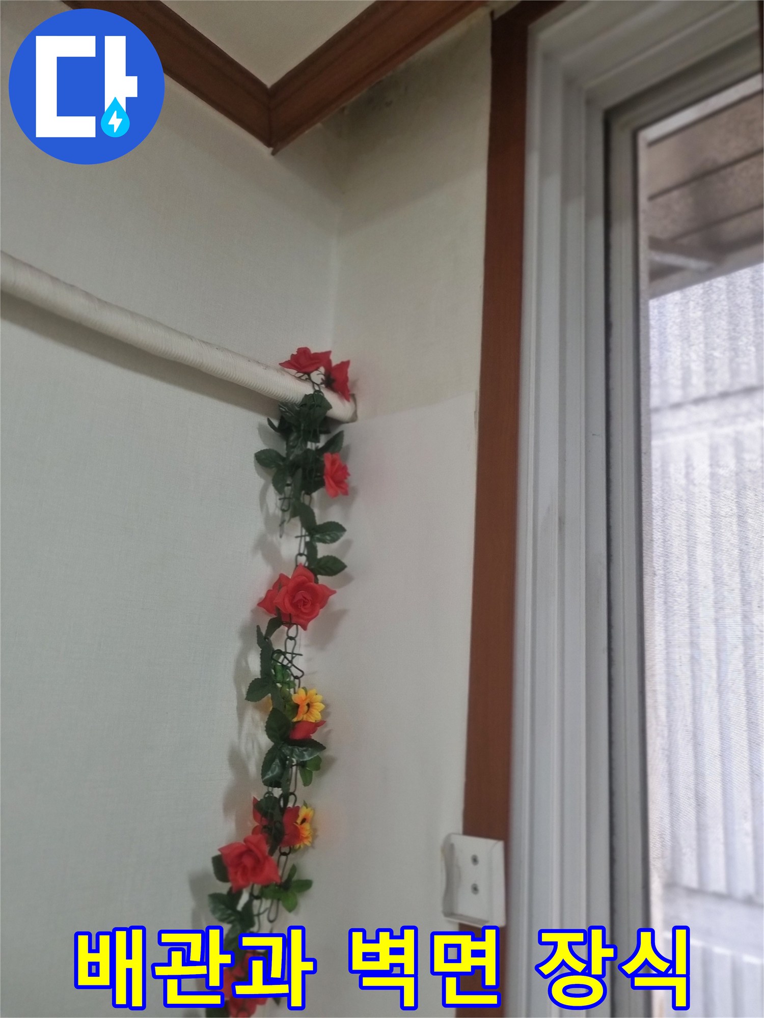 벽면에 설치된 흰색 관로와 꽃 장식물 사진