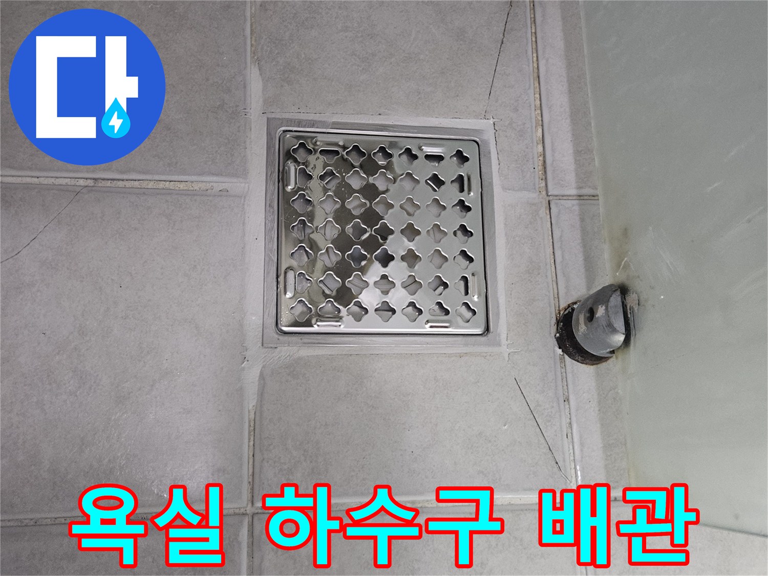 타일 사이의 균열과 노출된 오배수관 연결 상태