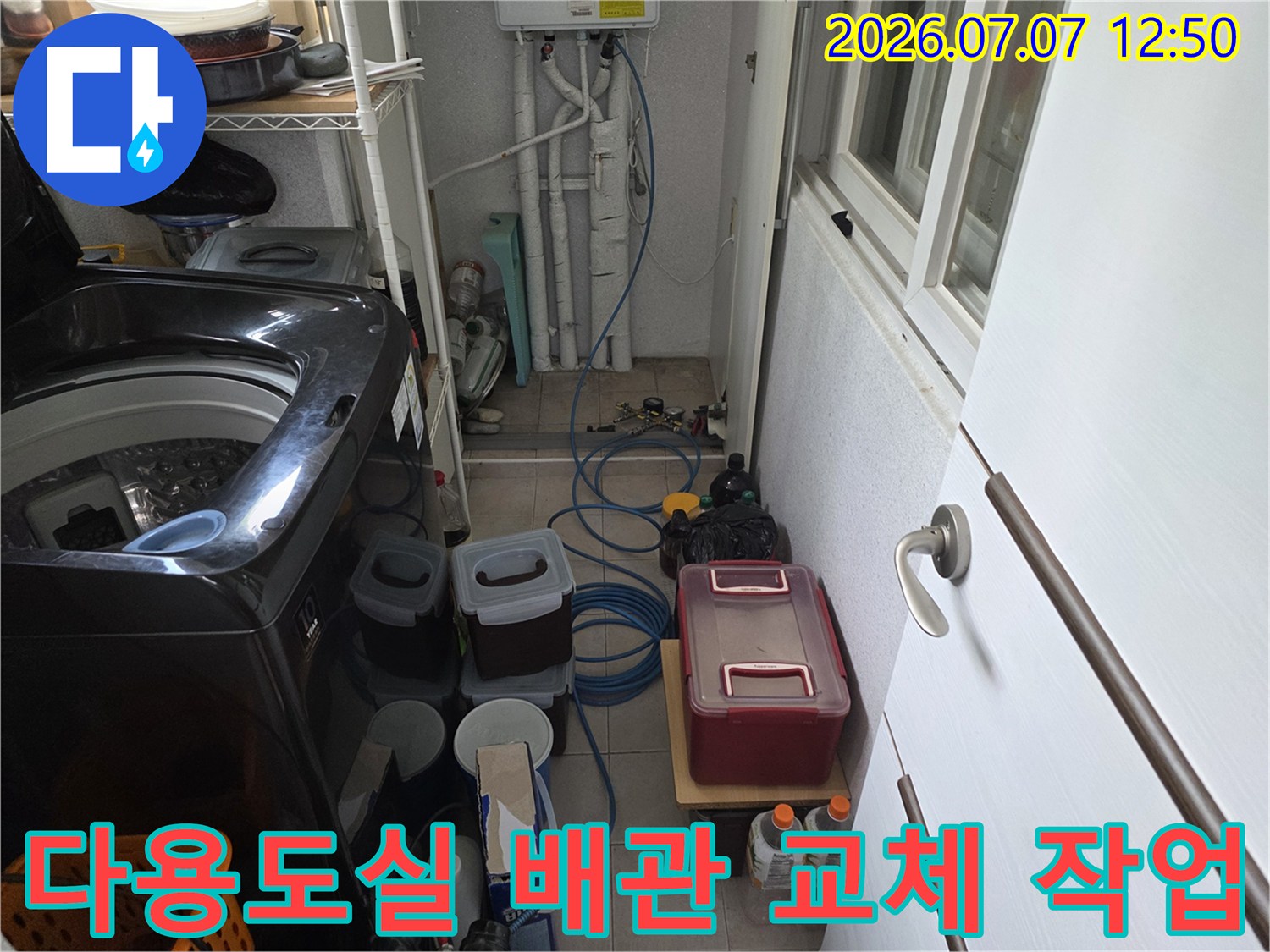 세탁기 옆에 배치된 파란색 호스와 빨간색 수리함이 있는 모습