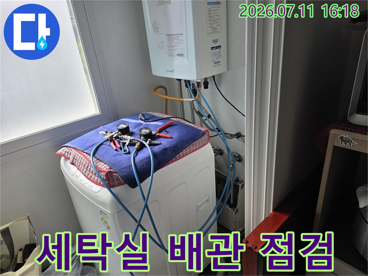 세탁기 위에 놓인 수건과 연결된 파란색 급수 호스 및 배관 점검 모습