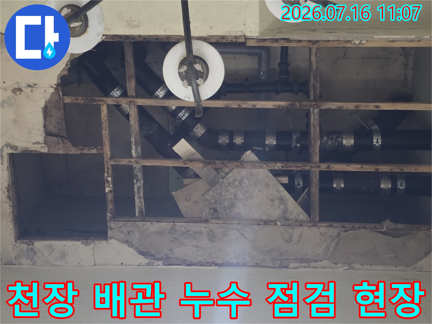 파손된 천장재를 제거하고 노출된 배관 연결 부위를 점검하는 모습
