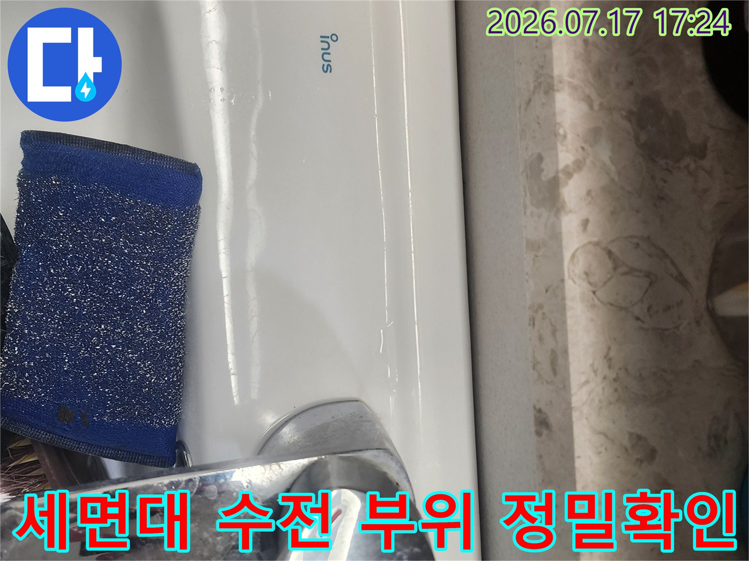 하얀 세면대와 금속 수도꼭지에 놓인 파란색 스펀지 도구
