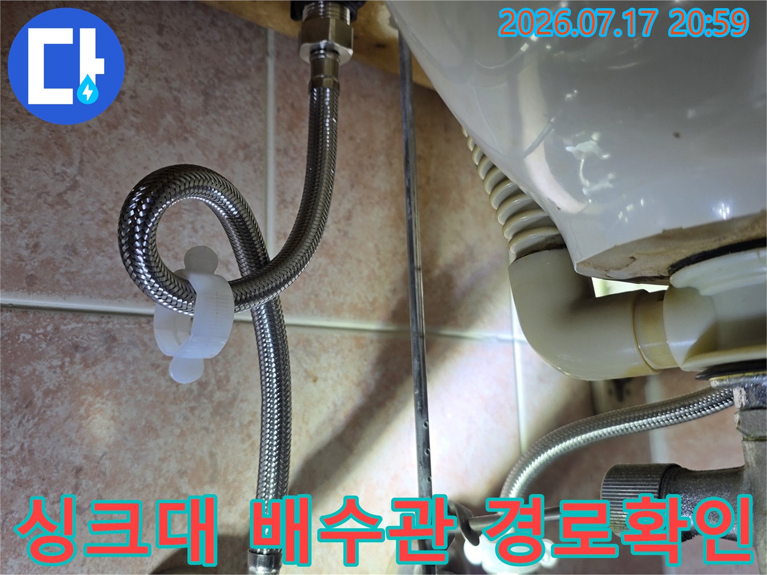 싱크대 밑에 설치된 주름형 배수 호스의 연결부 및 트렌치 구간 점검용 사진