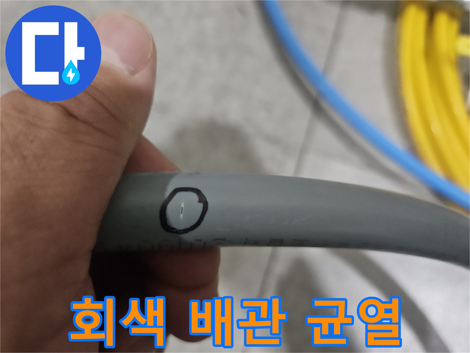 손으로 잡고 있는 회색 배관의 결함 부위